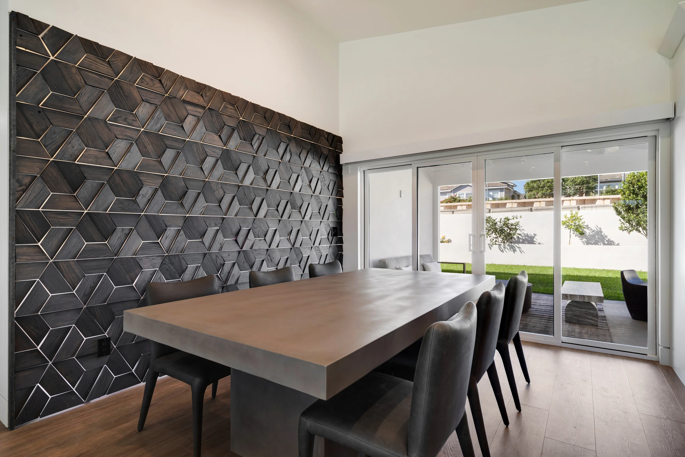 Dining table beside dimensional dark wood feature wall and sliding glass doors