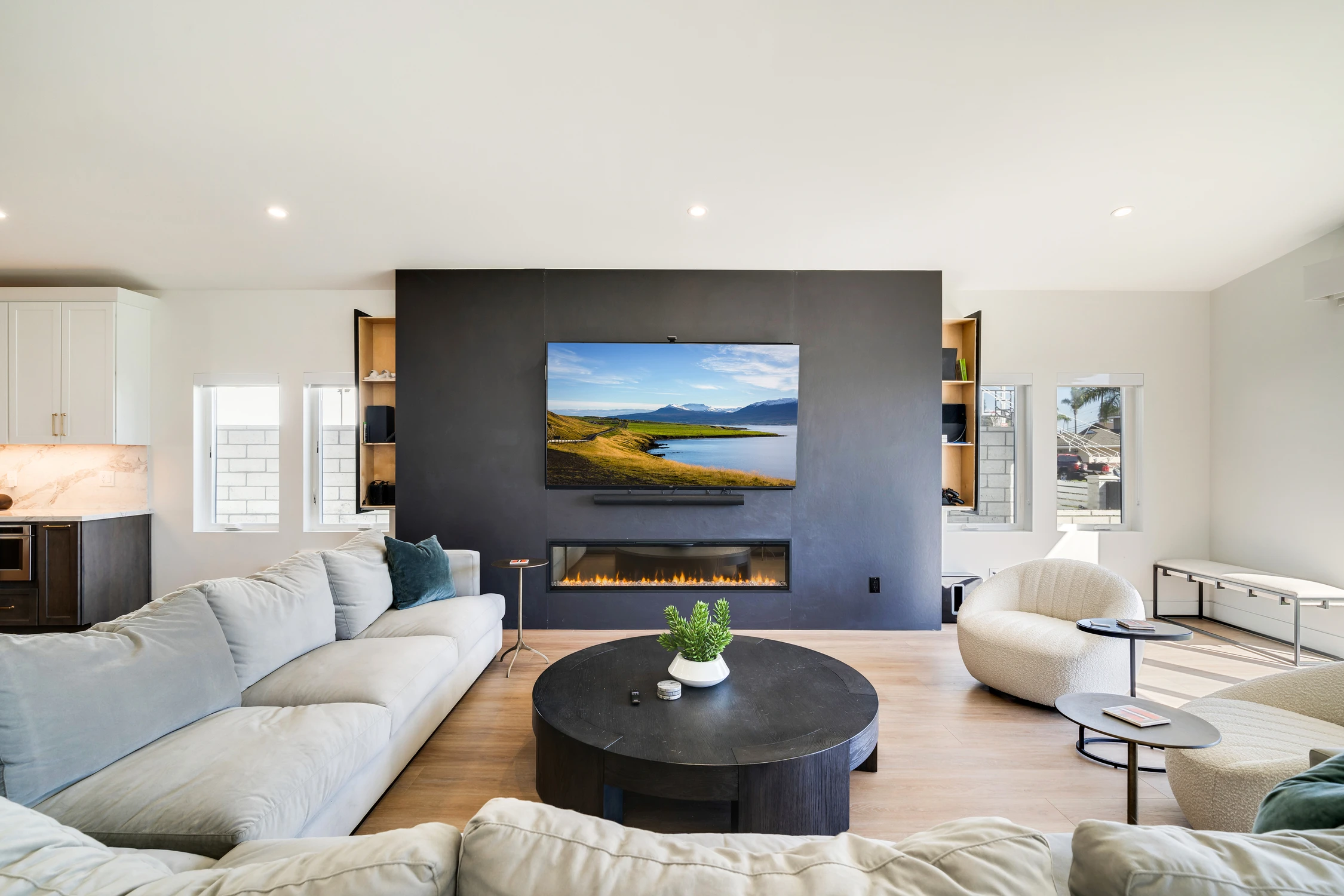 Living room with white sectional, black media wall, and round coffee table