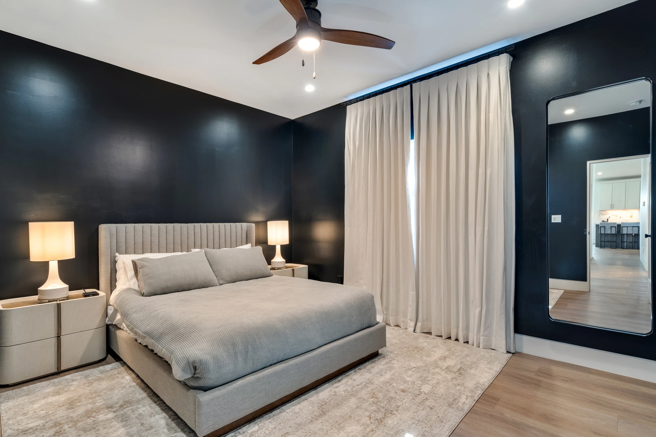 Bedroom with dark walls, upholstered bed, and white drapery