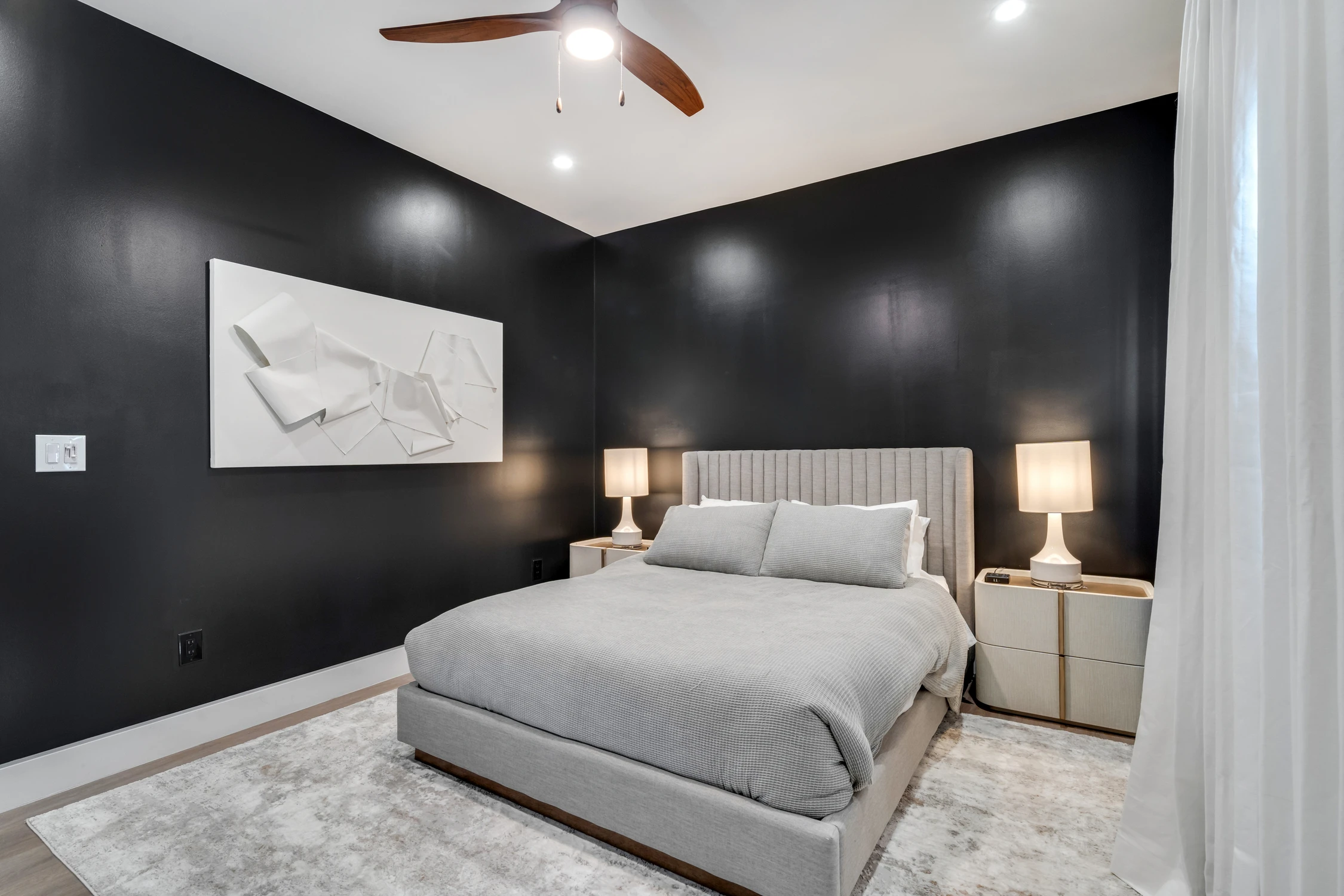 Bedroom with dark walls, upholstered bed, and sculptural wall art