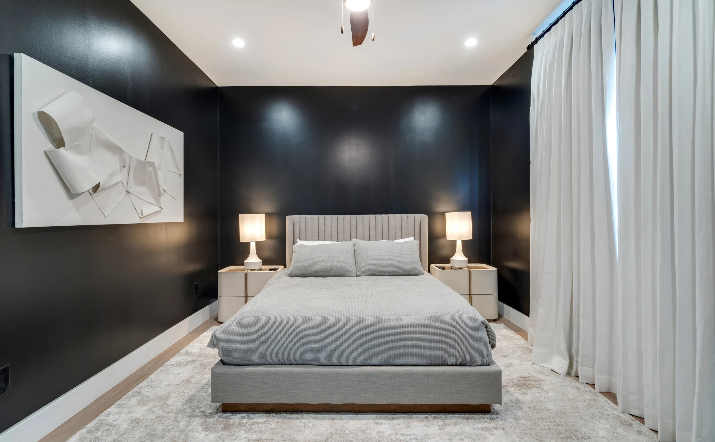 Bedroom with dark walls, upholstered bed, and white drapery