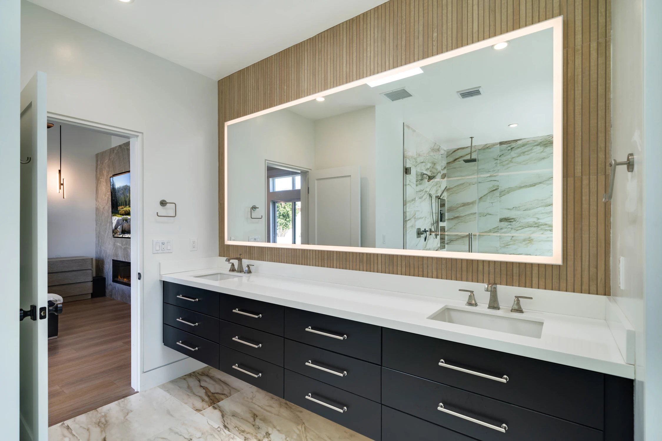 Bathroom double vanity with black cabinetry, white counter, and large mirror