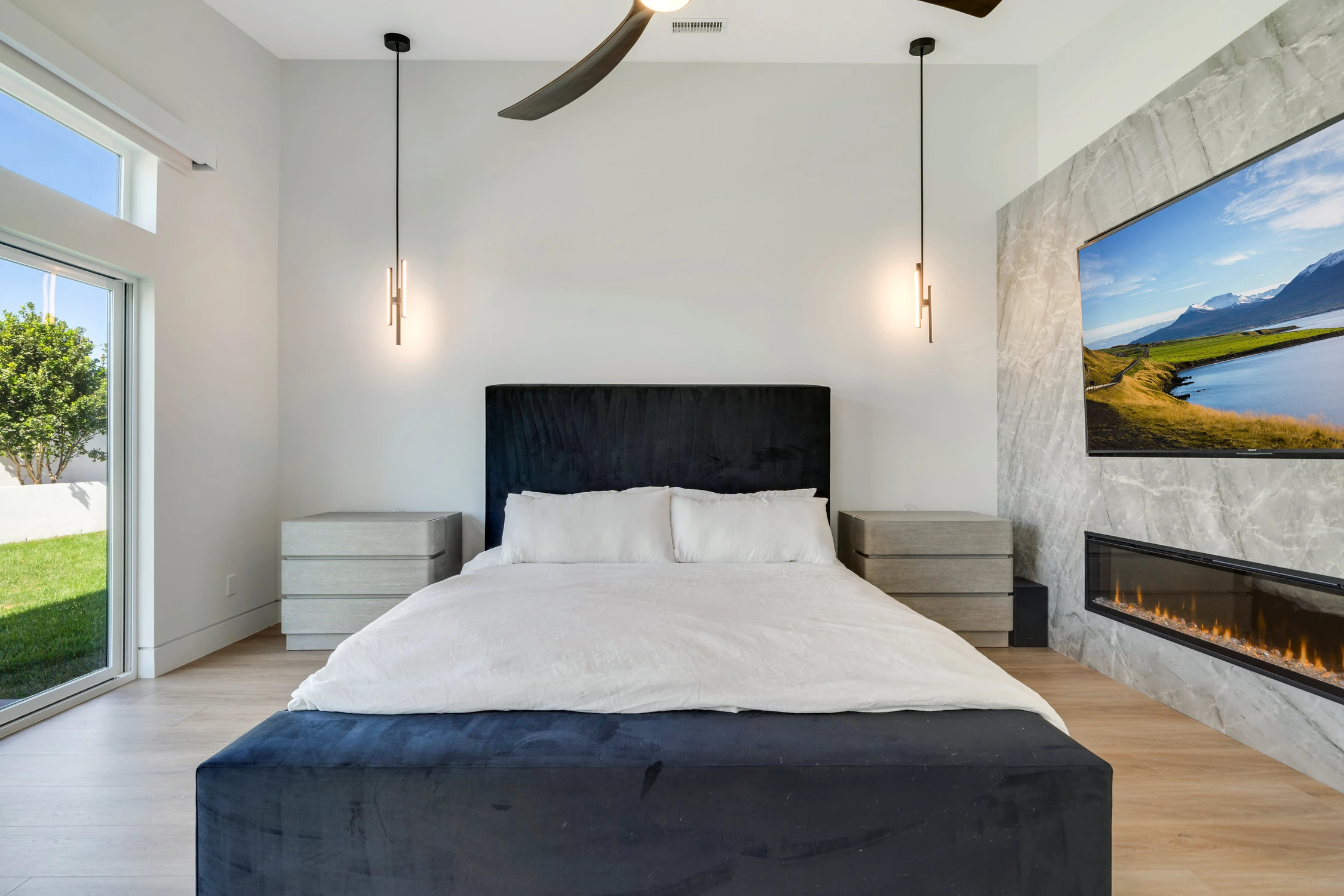 Primary bedroom with black bed, marble fireplace, and sliding glass door
