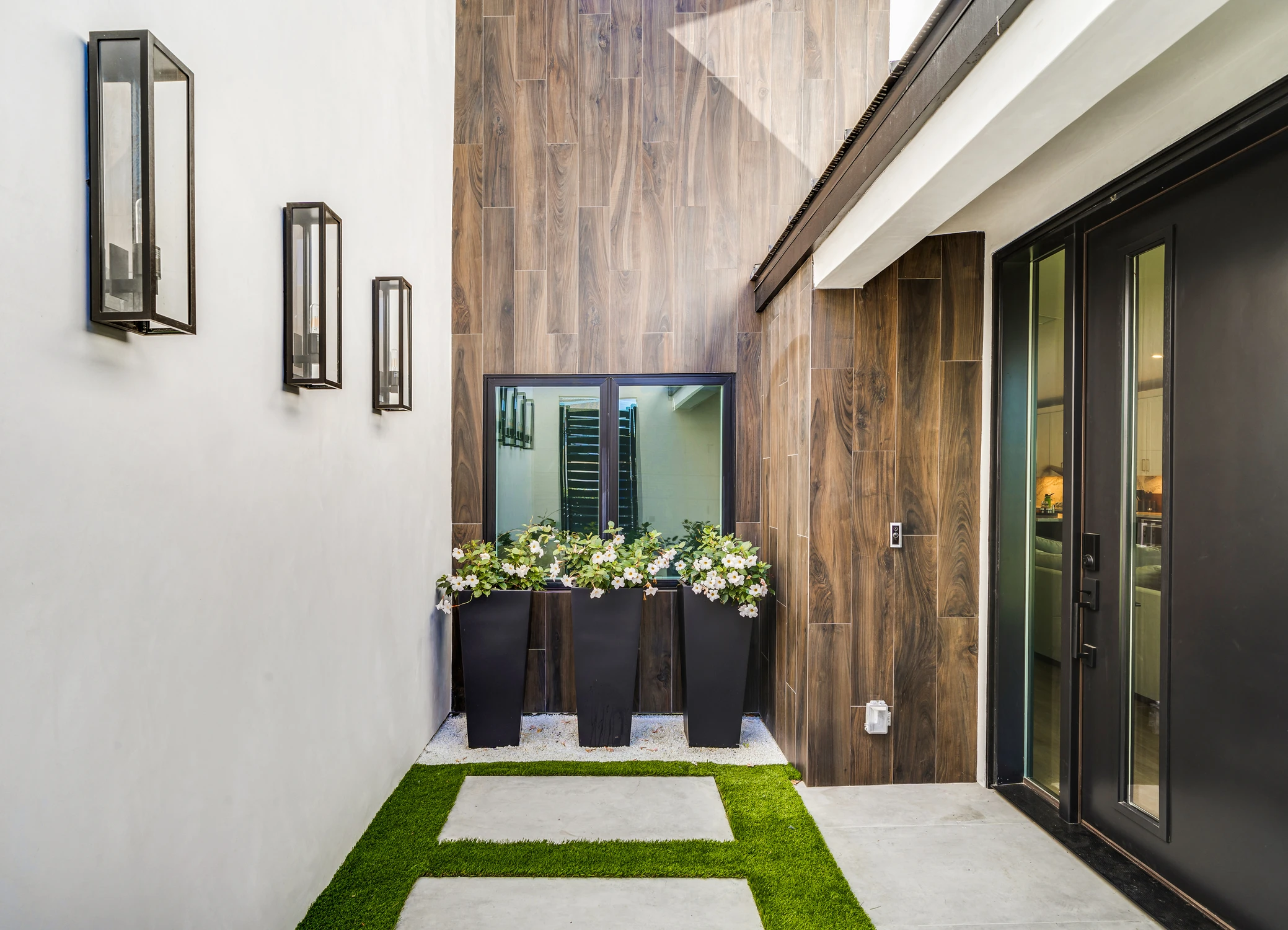 Front entry courtyard with wood cladding, black door, and planters