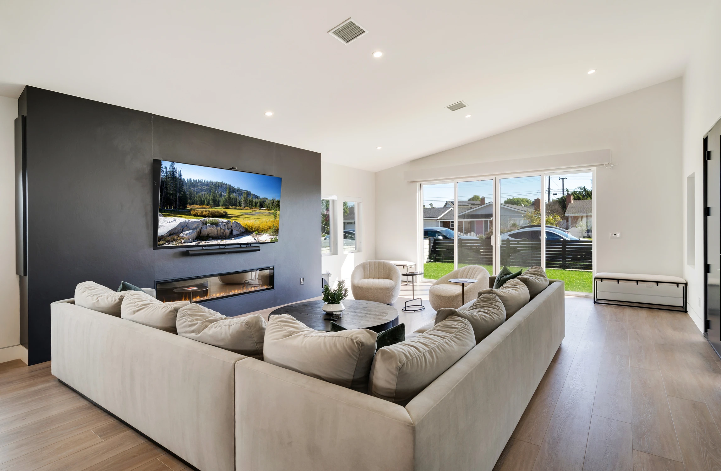 Living room with white sectional, black media wall, and sliding glass doors