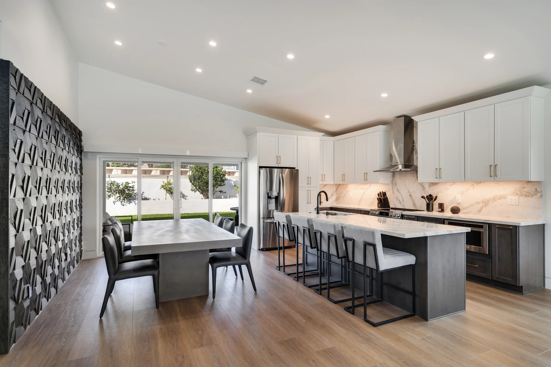 Open kitchen and dining area with marble island and dimensional wood wall