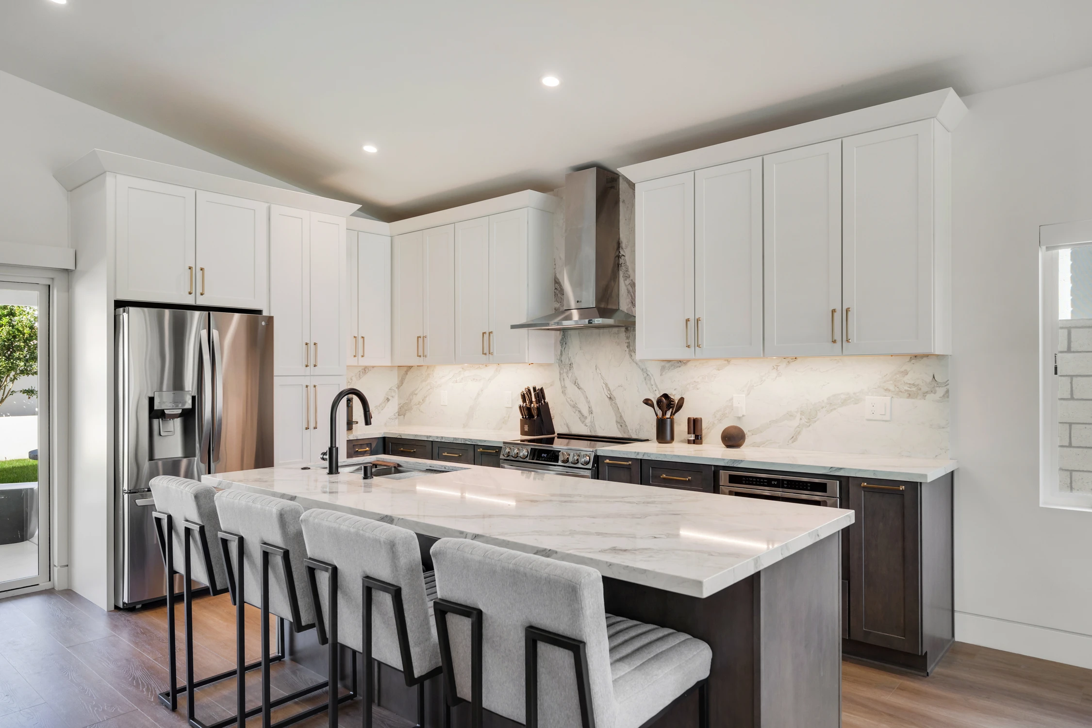 Kitchen with white upper cabinetry, marble island, and stainless range