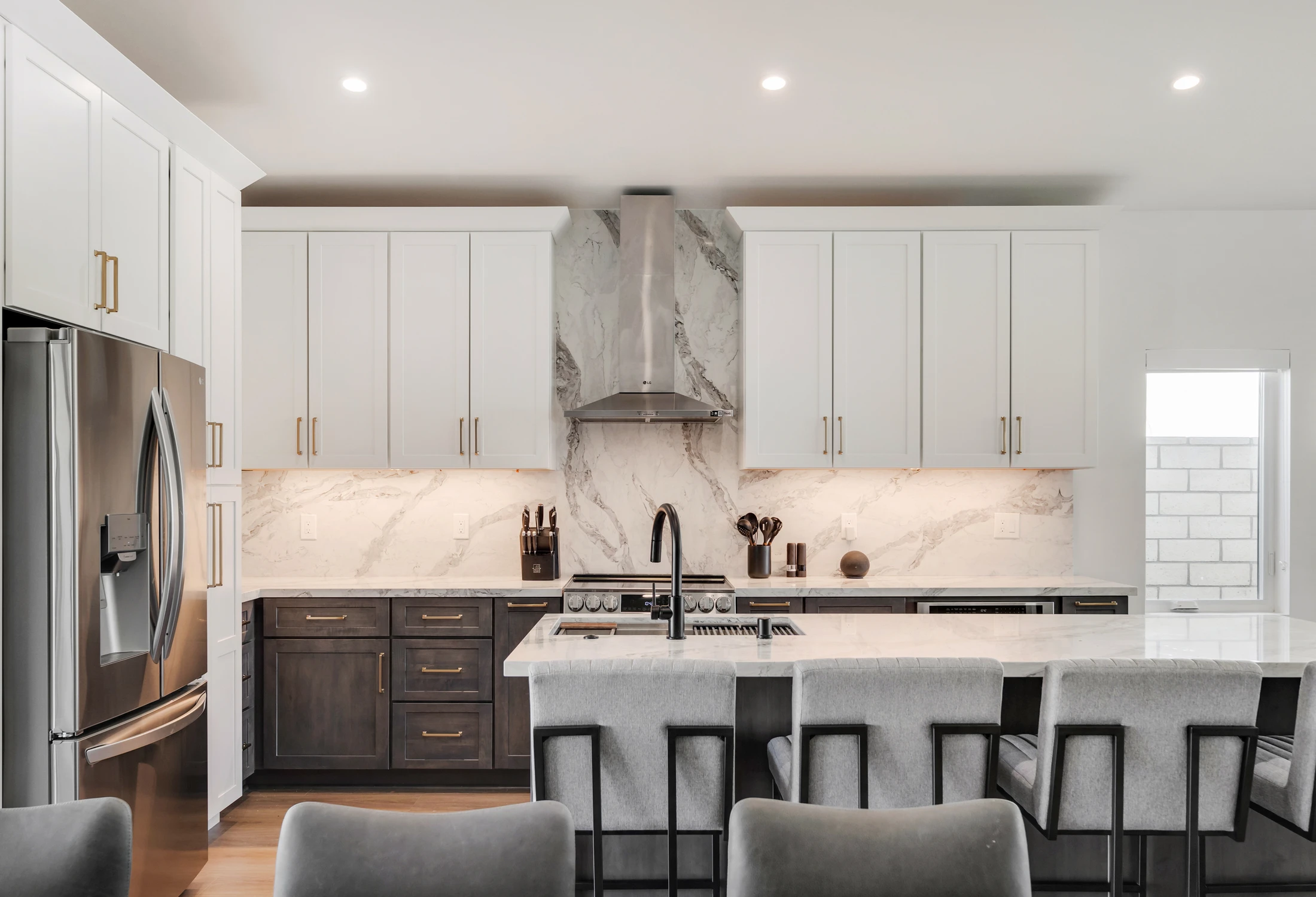 Kitchen range wall with white cabinetry, marble backsplash, and black faucet