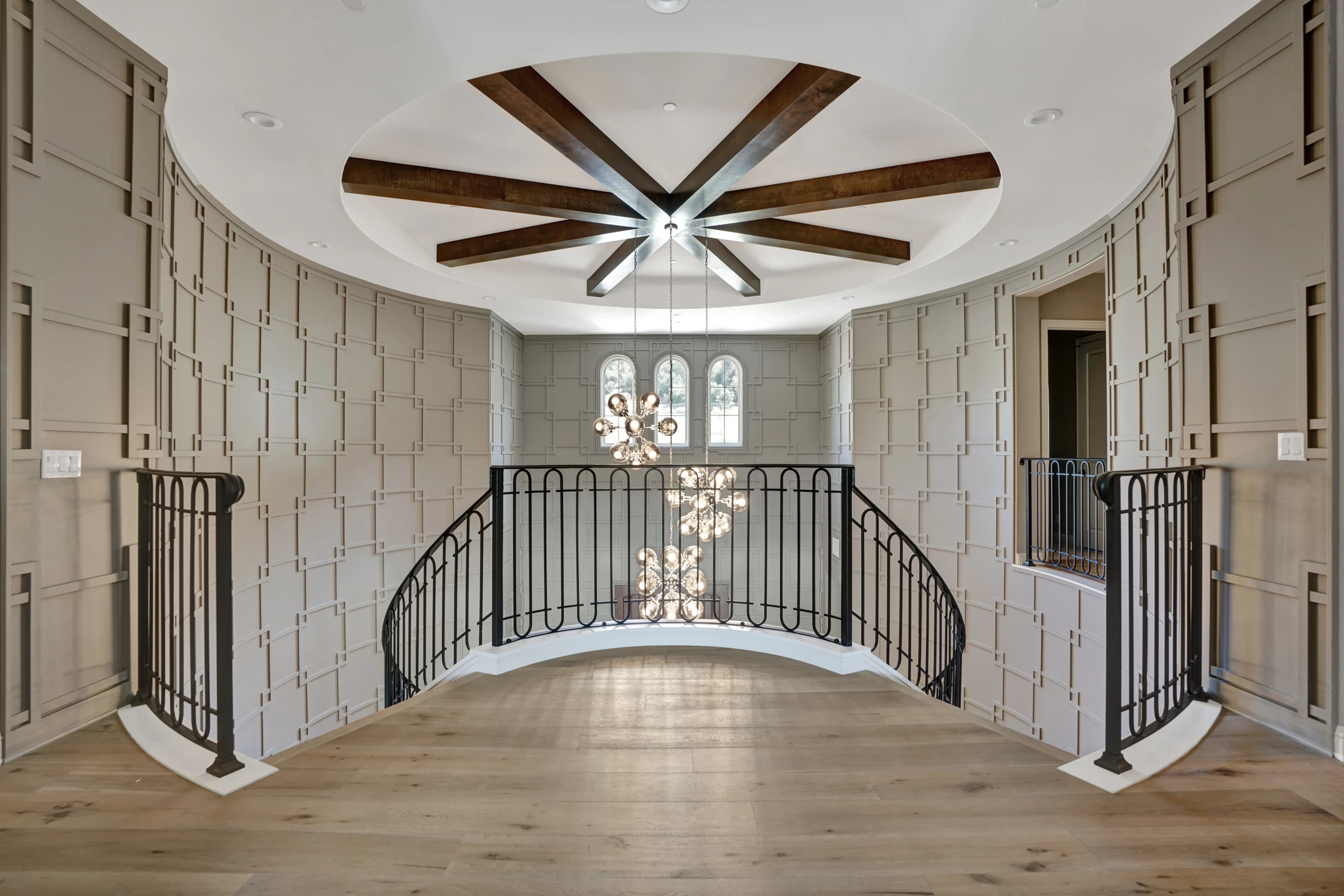 Grand foyer with curved double staircase and geometric wallcovering