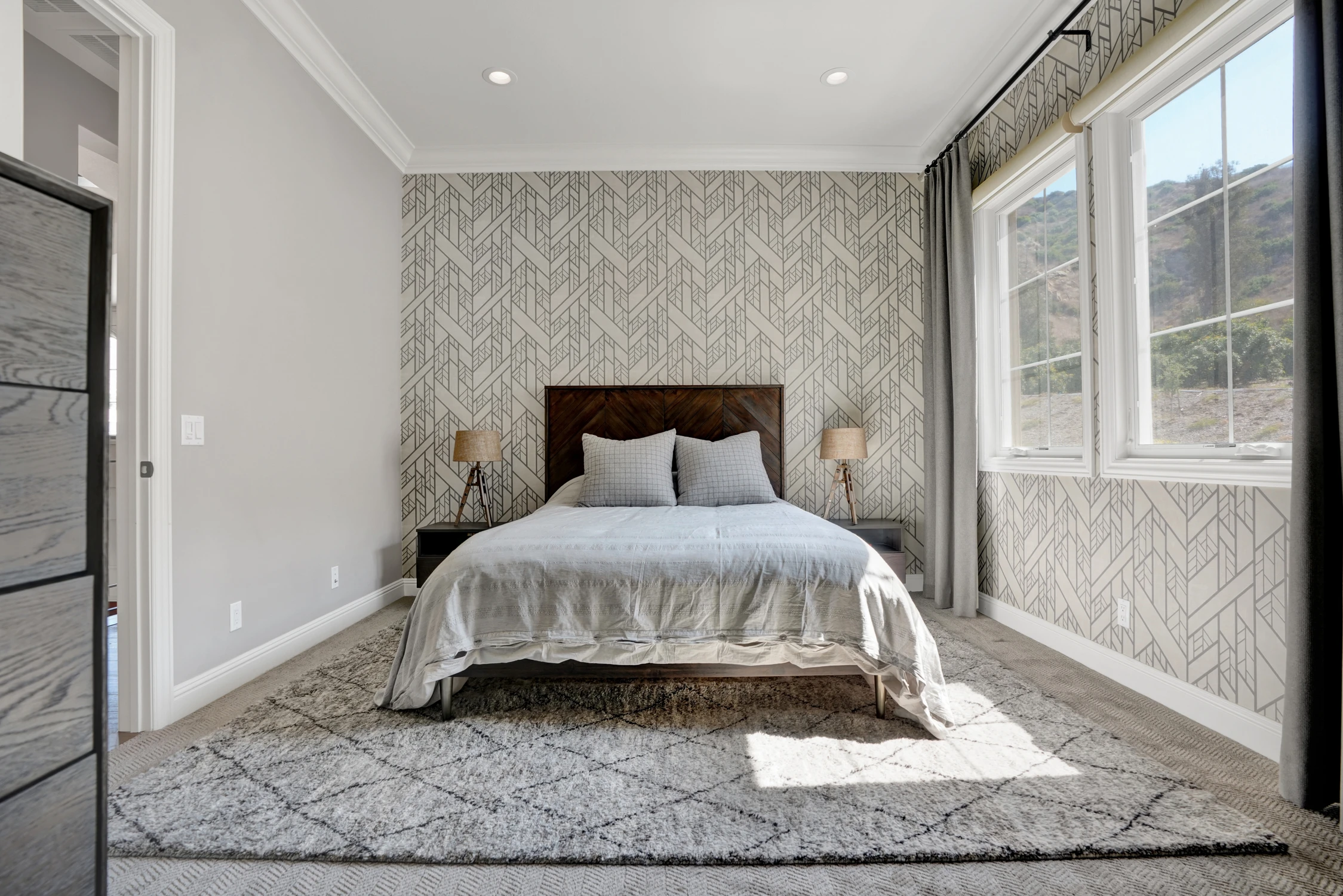 Bedroom with gray upholstered bed and patterned wallpaper
