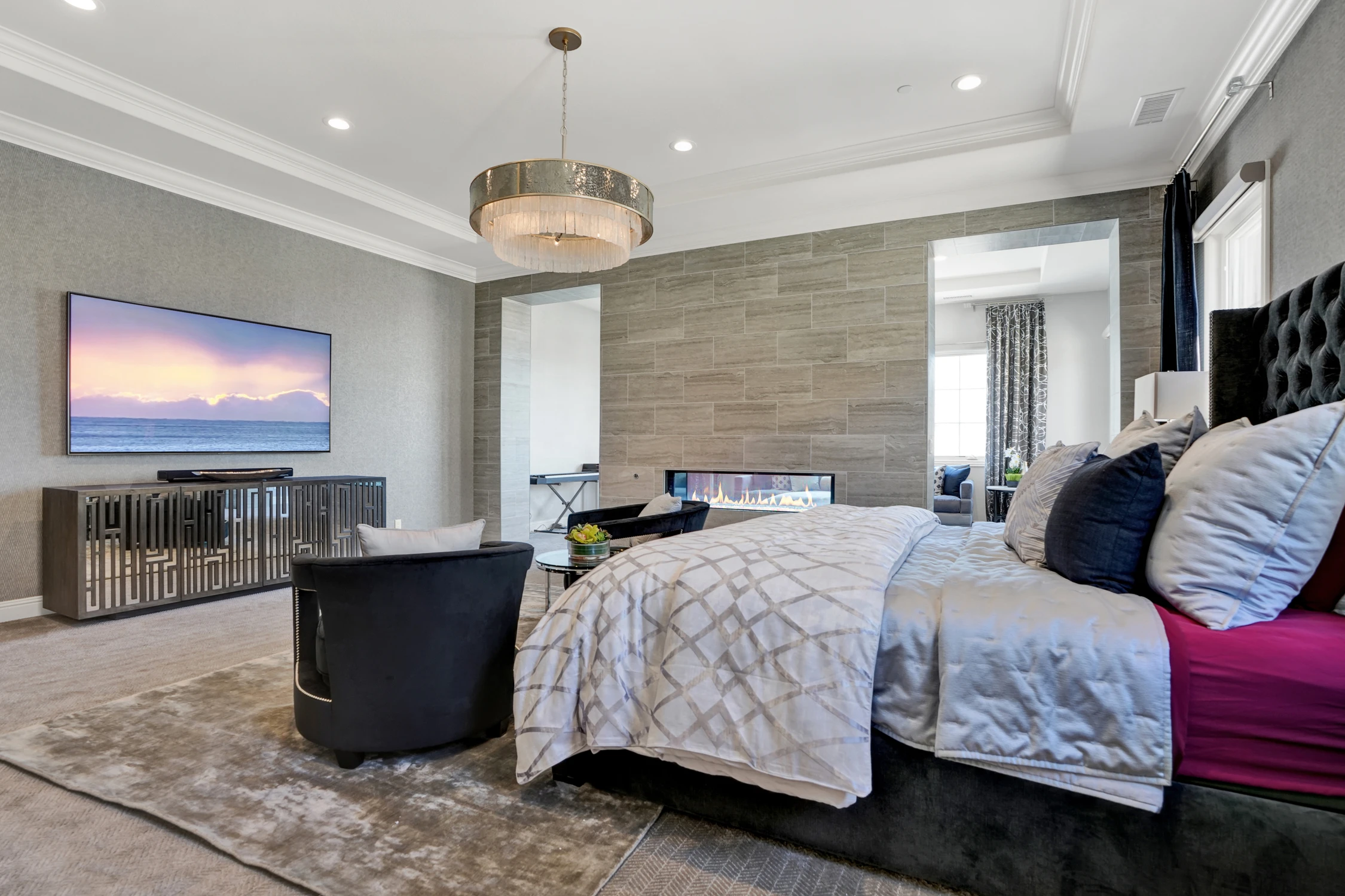 Master bedroom with gray bedding and television wall