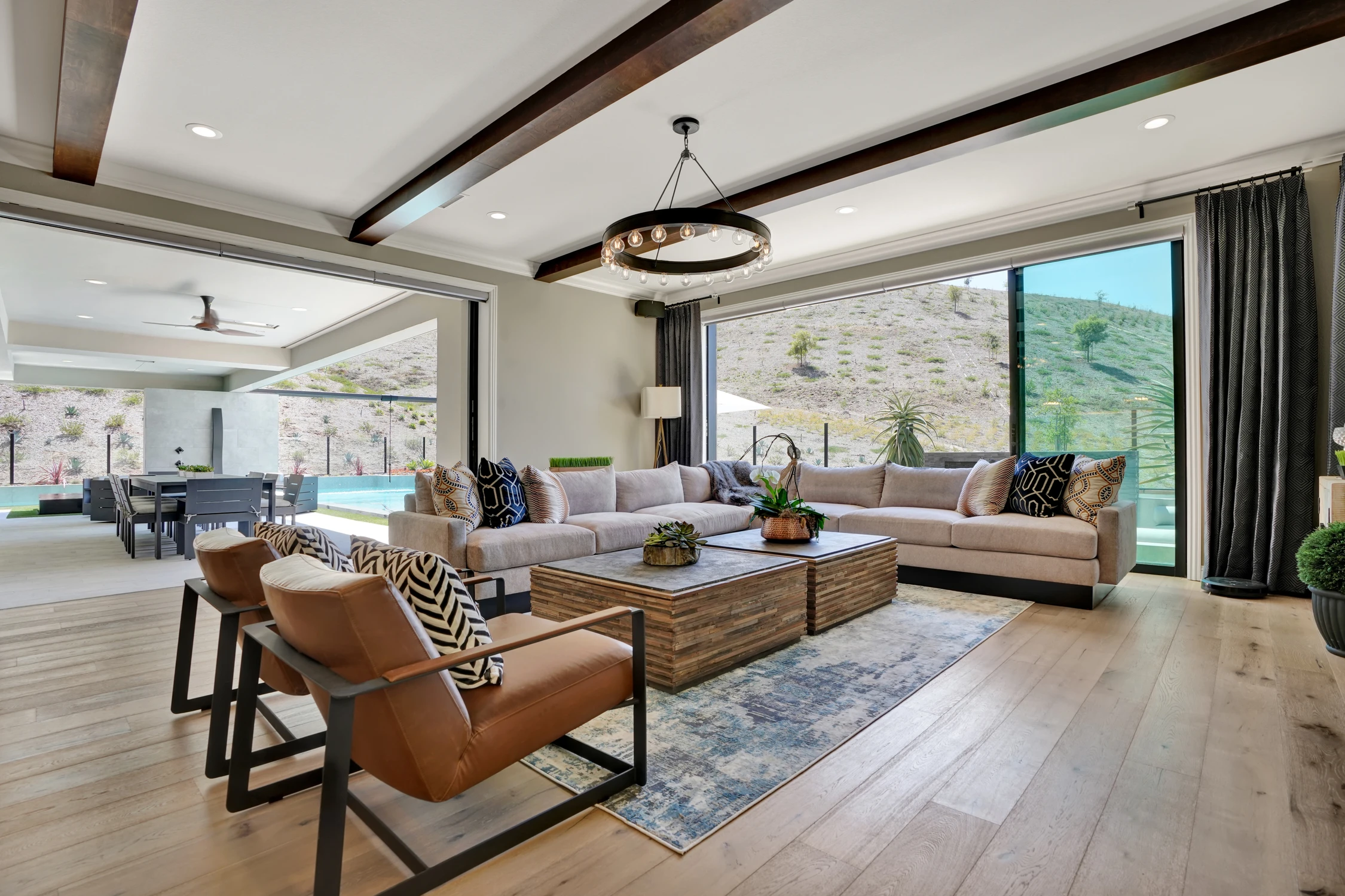 Great room with exposed beams, kitchen, and patterned sofa