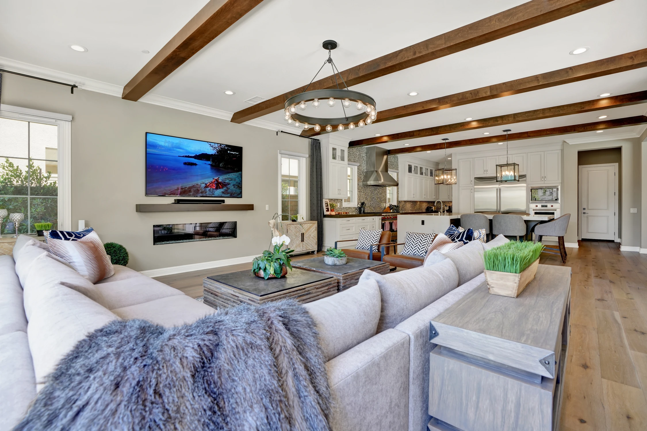 Living room with pale sectional, exposed beams, and open kitchen