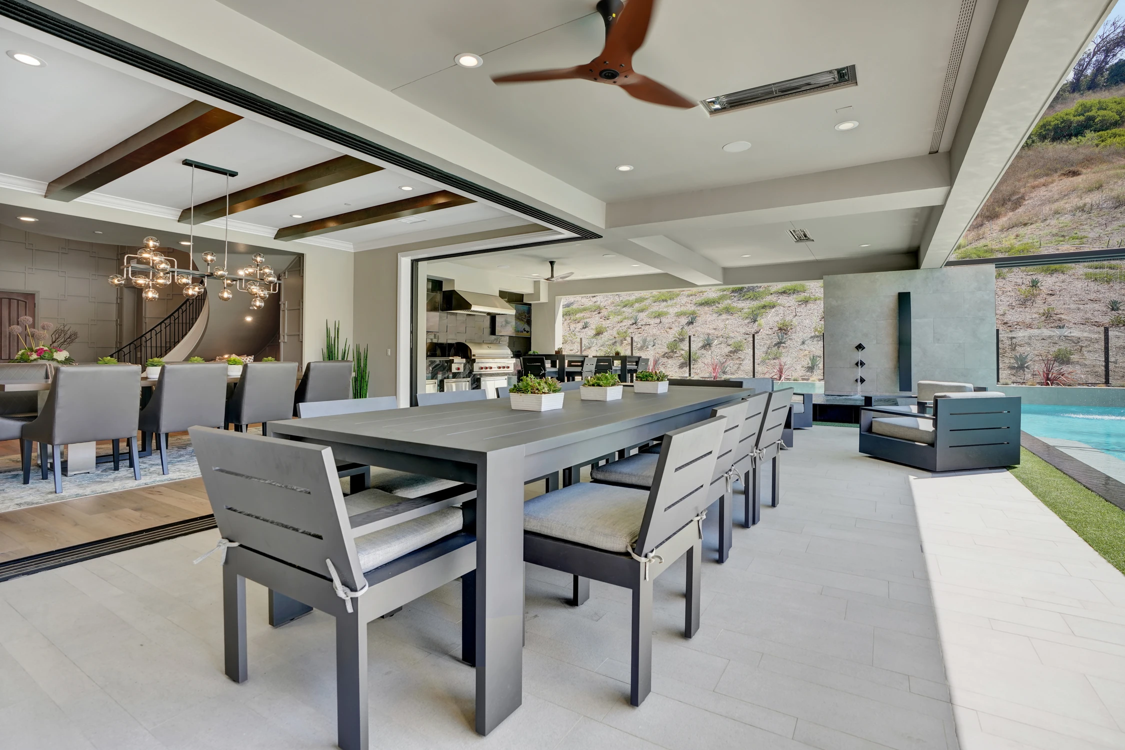 Covered outdoor dining table beside pool and mountain view