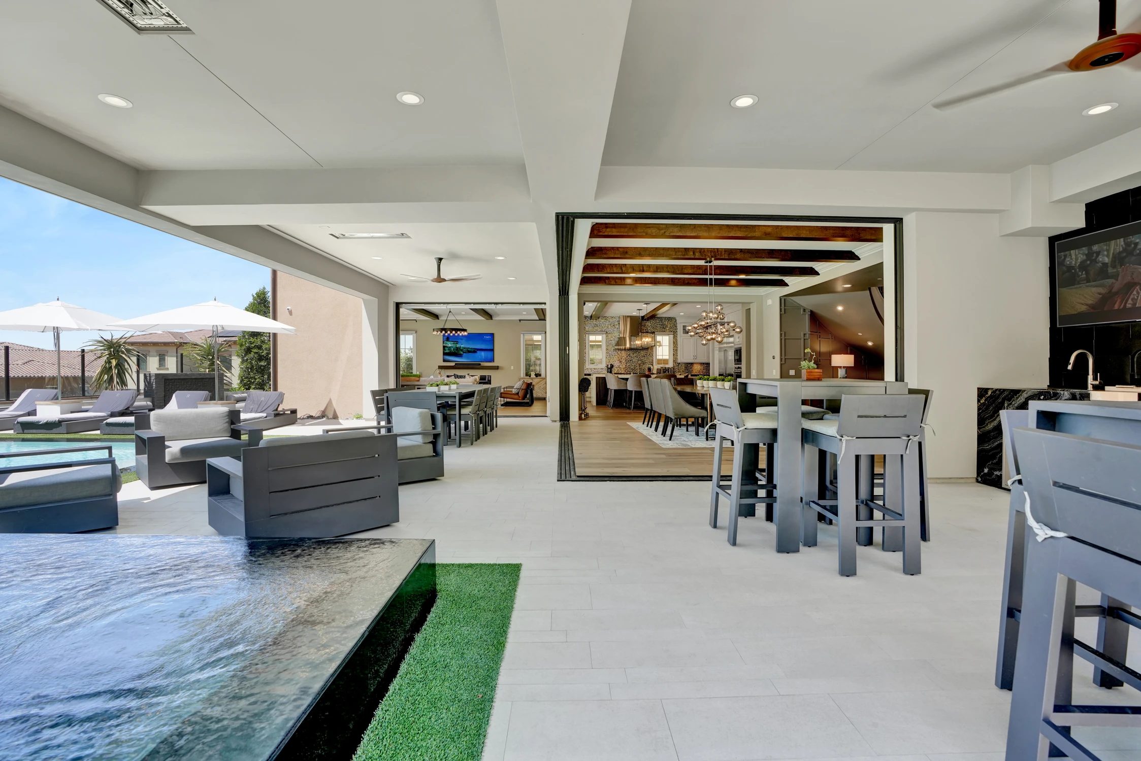 Covered patio bar beside pool and outdoor kitchen