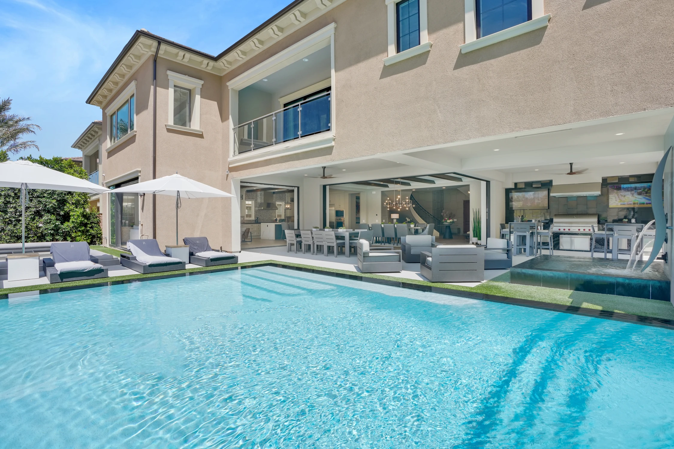 Backyard pool with lounge chairs, covered patio, and outdoor kitchen