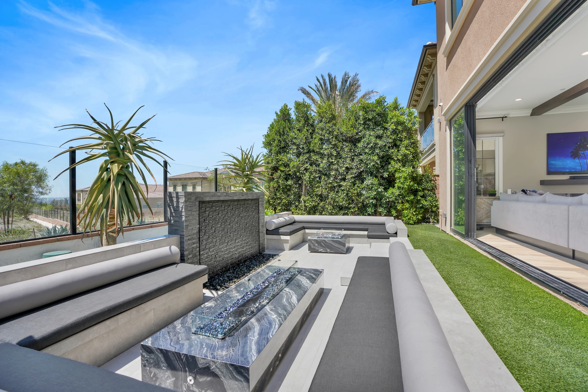 Outdoor firepit beside modern seating and palm trees