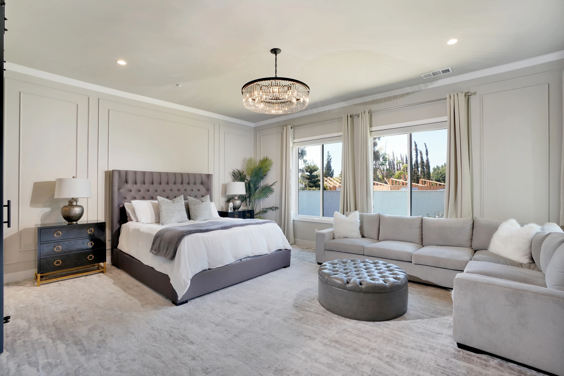 Bedroom with large gray sectional, upholstered bed, and wall-mounted television