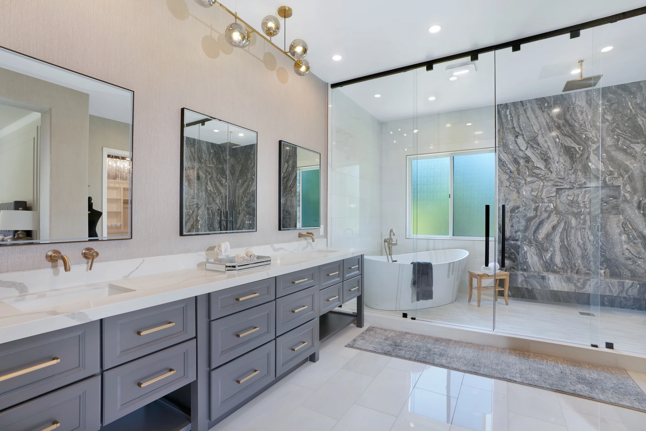 Primary bathroom with long gray vanity, glass shower, and dark large-format slab wall