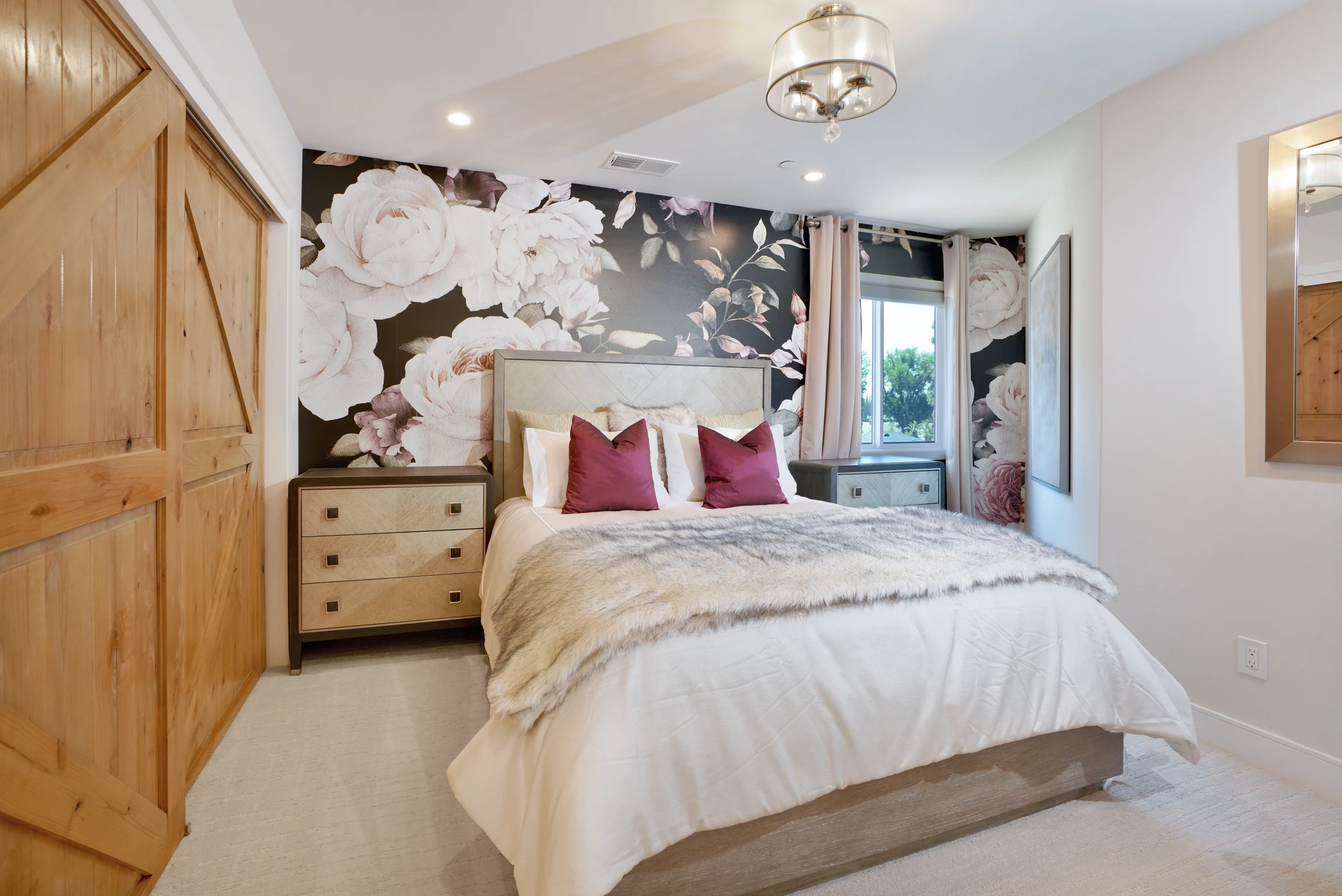 Bedroom with floral wall mural, pale wood cabinetry, and magenta pillows