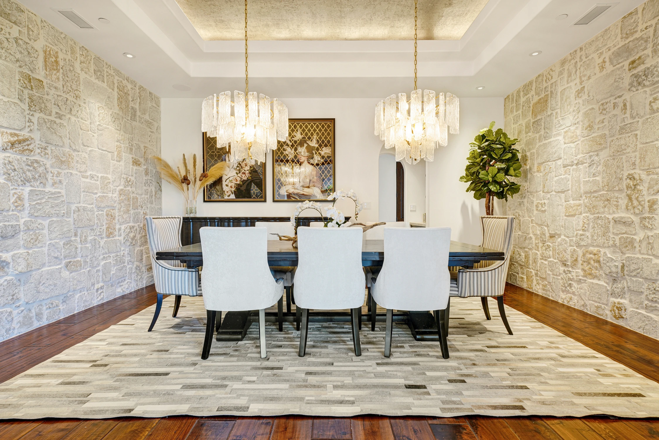 Dining room with stone walls, crystal chandeliers, and white chairs