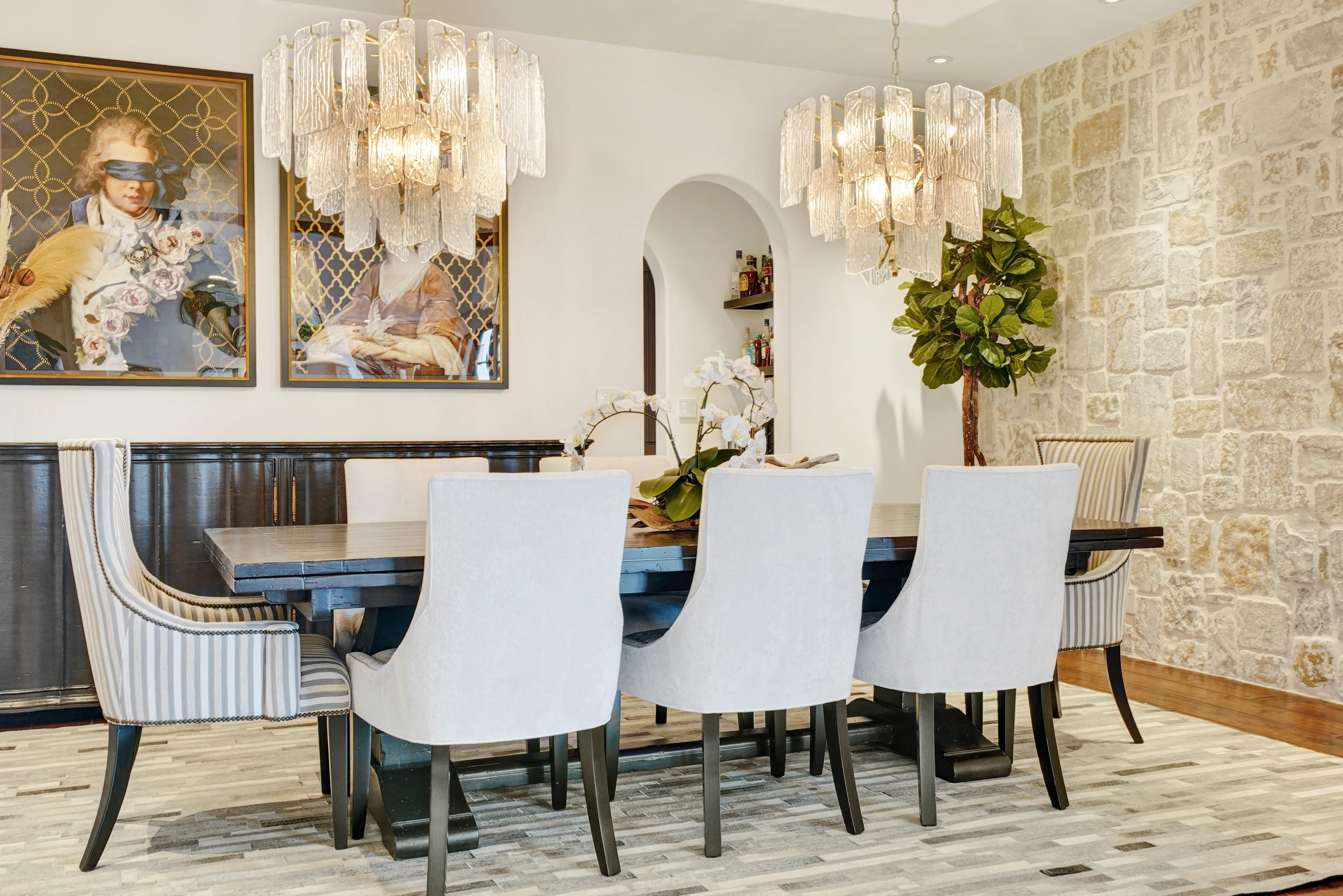 Dining table beneath crystal chandeliers and framed artwork