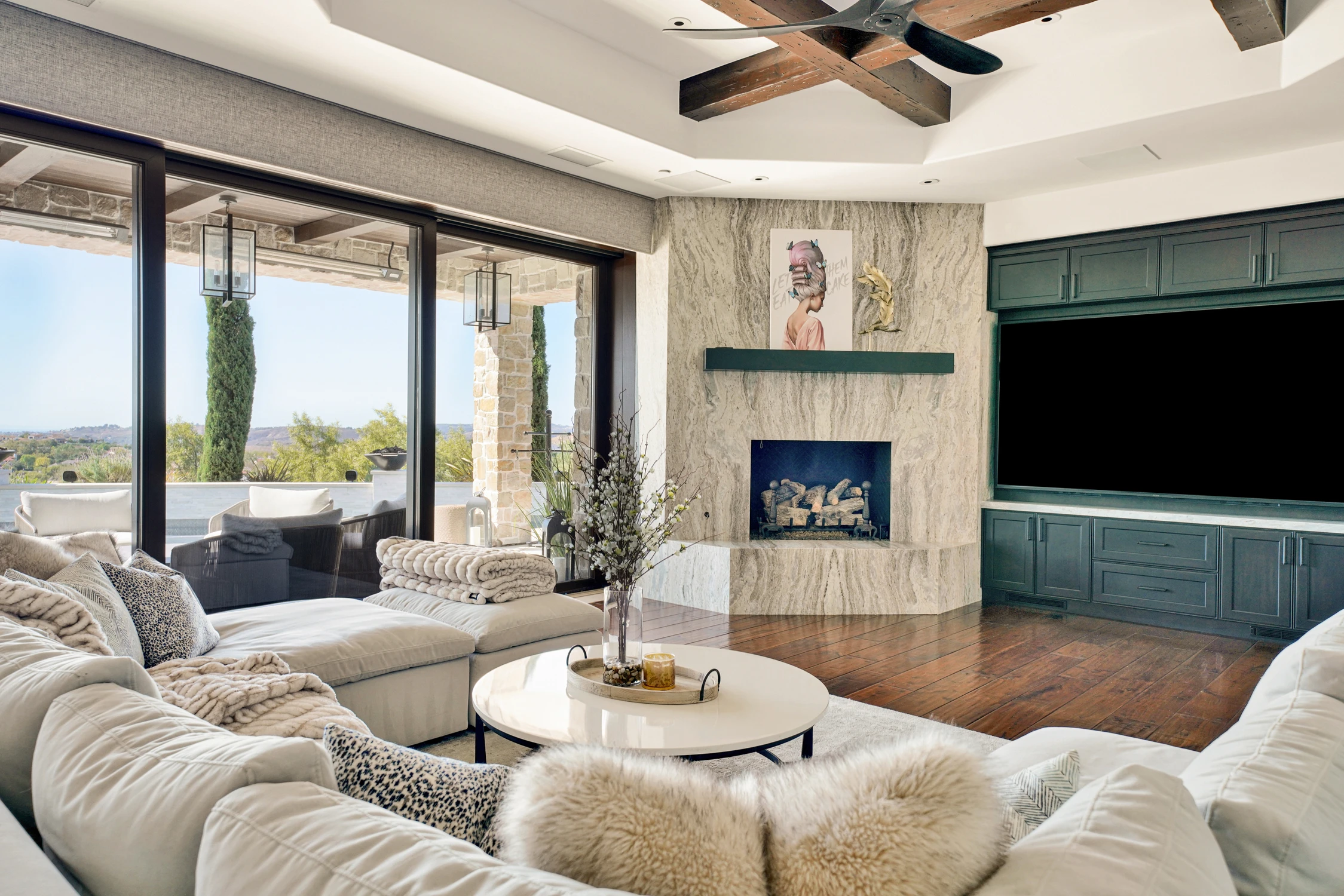 Living room with white seating, stone fireplace, and dark built-in cabinet