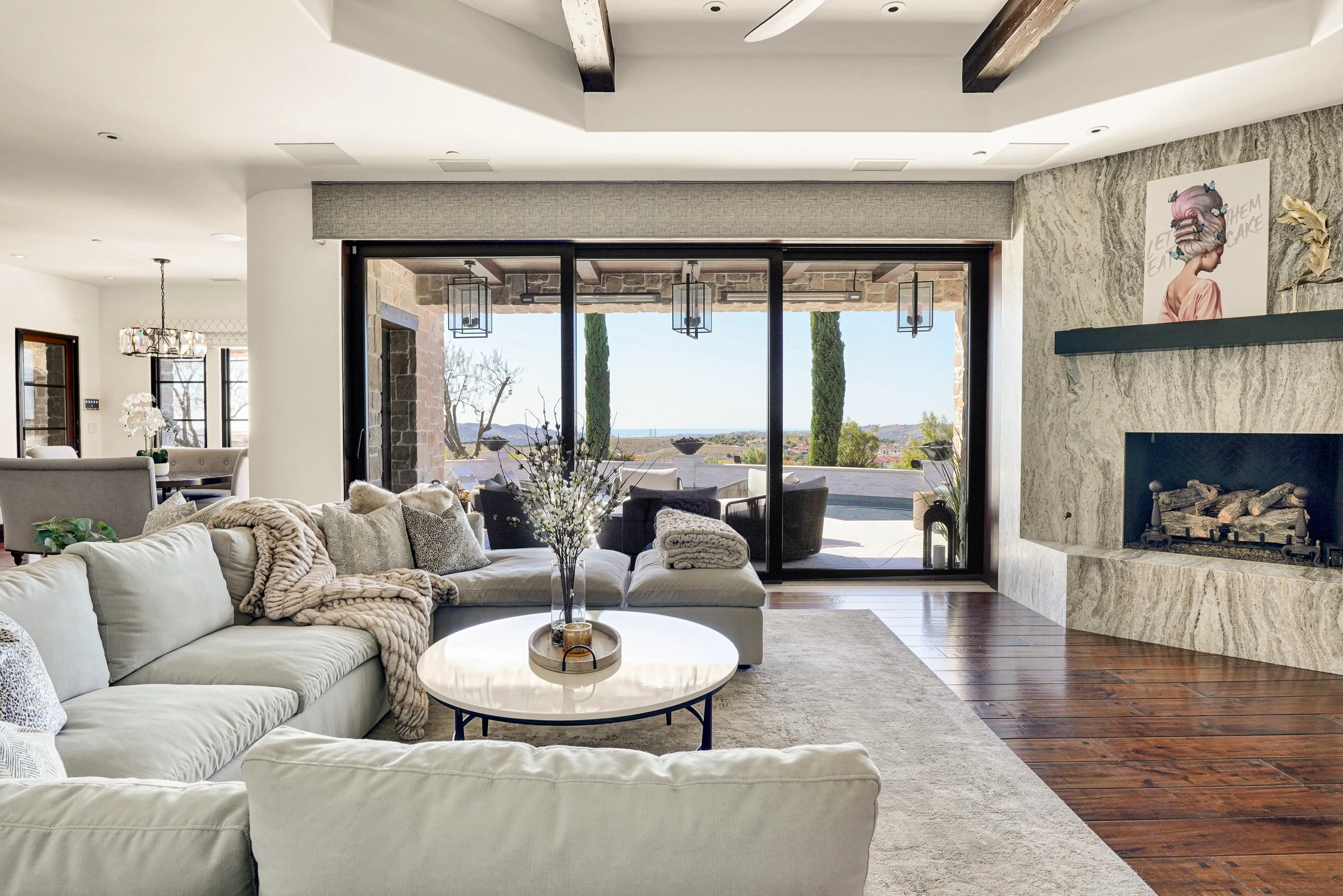 Living room with white sectional, stone fireplace, and patio doors