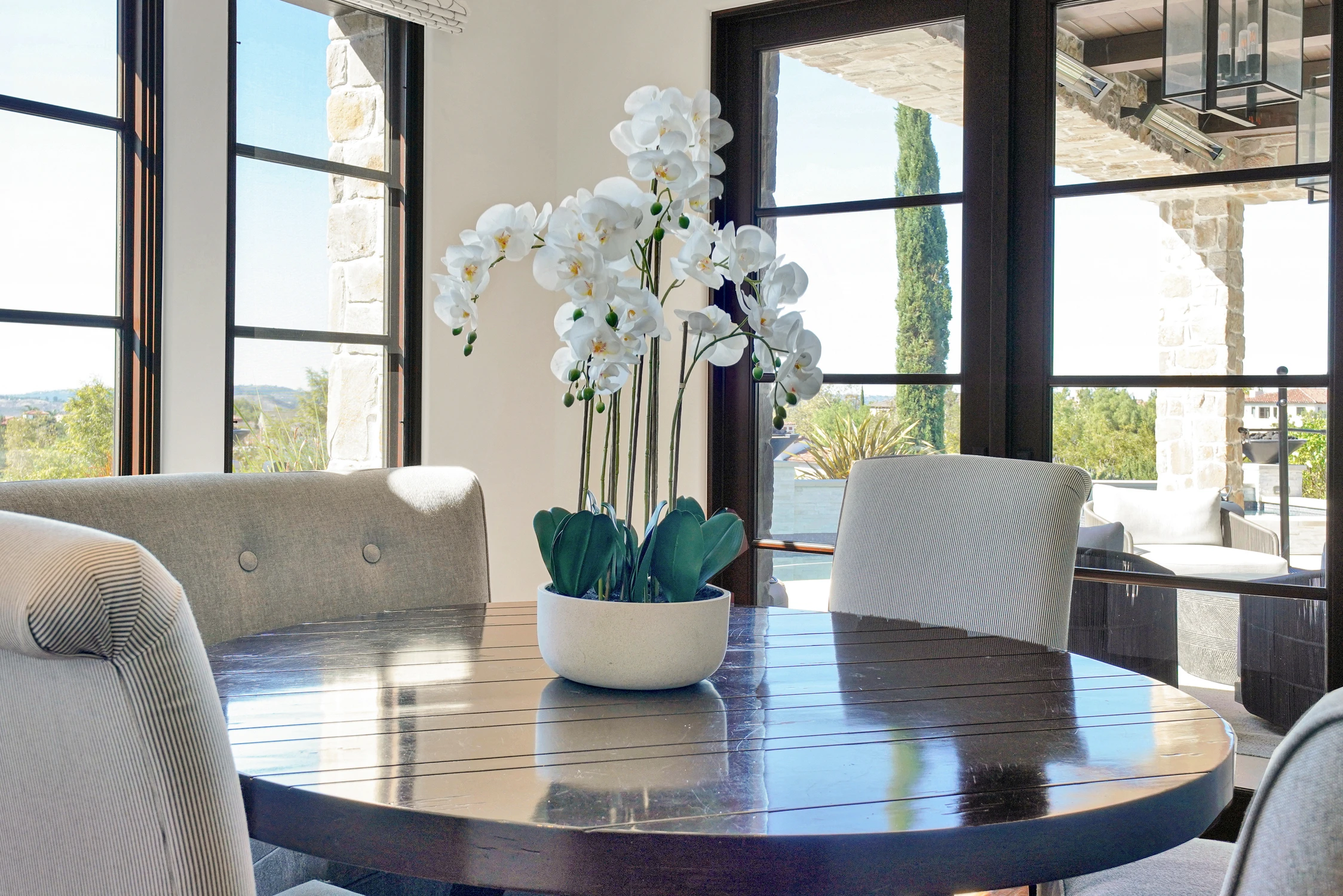Round dining table with orchid and black-framed windows