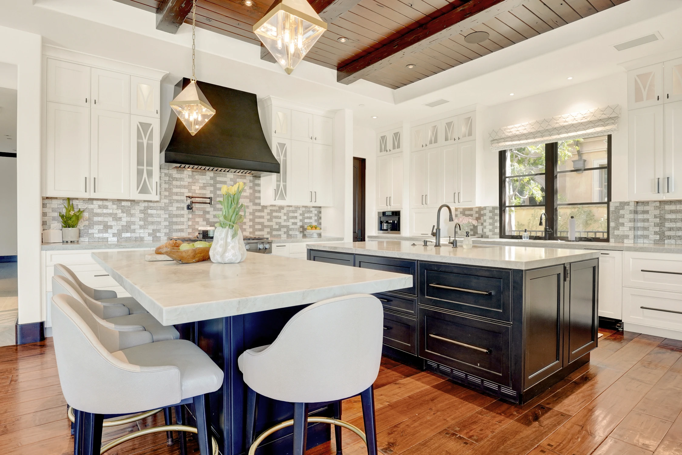 Kitchen island with black range hood and wood ceiling beams