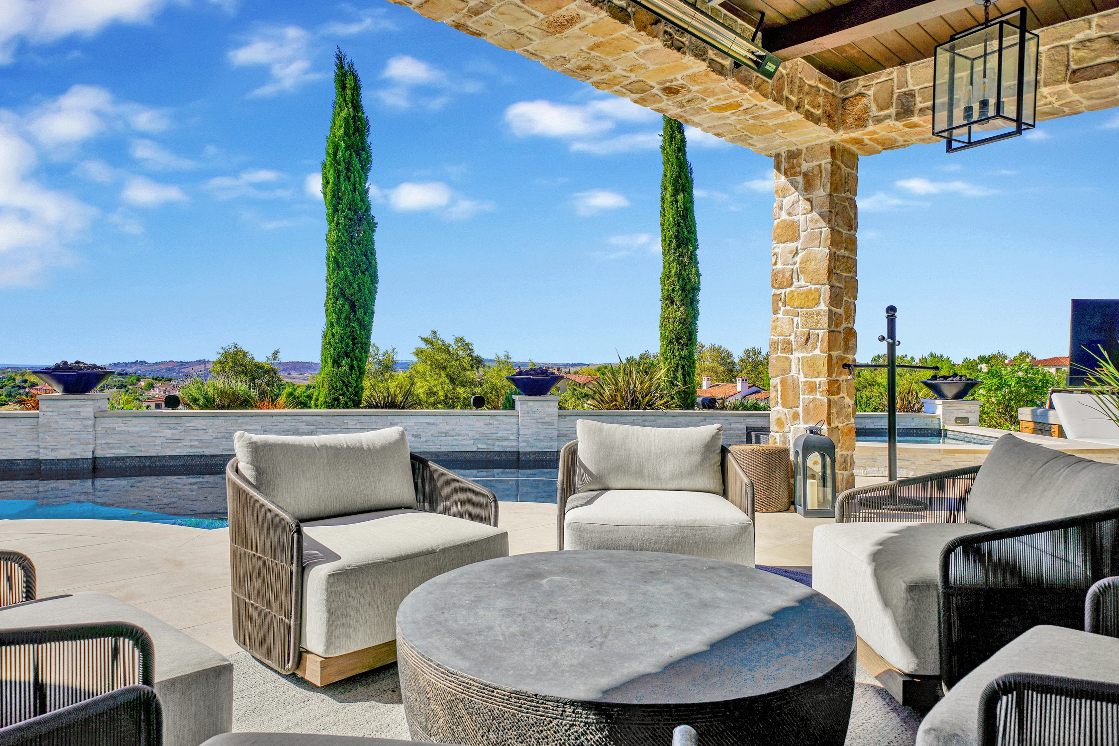 Covered patio seating with stone columns and pool view