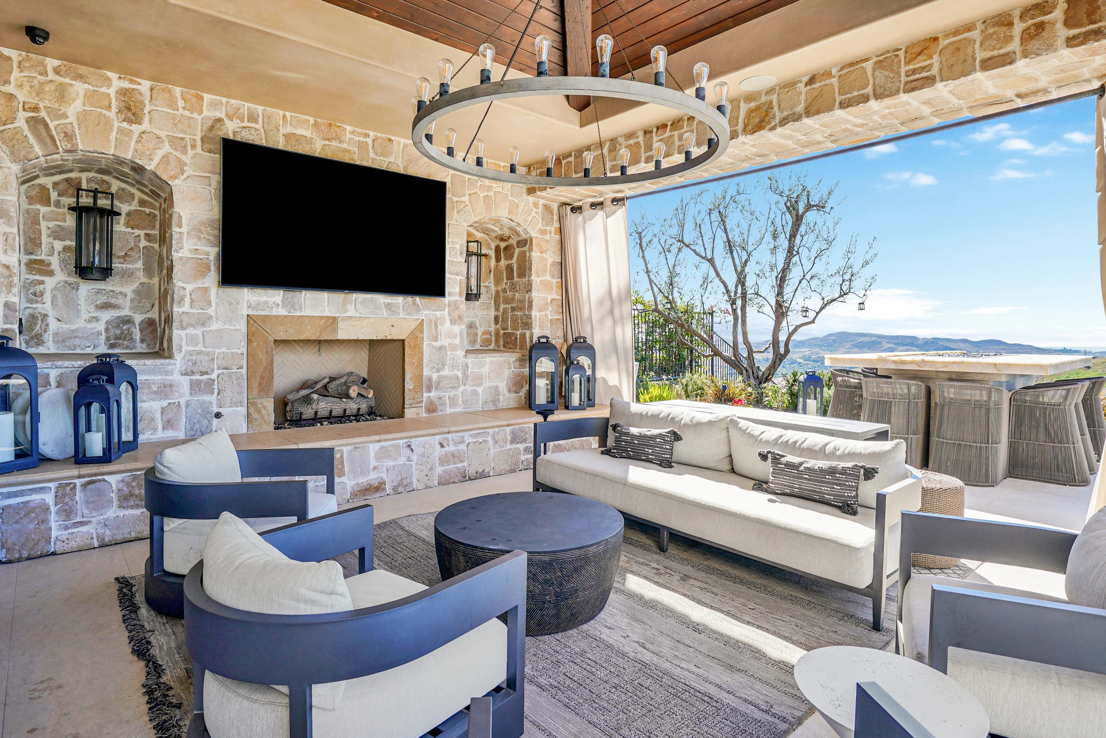 Covered patio with stone fireplace, television, and outdoor bar