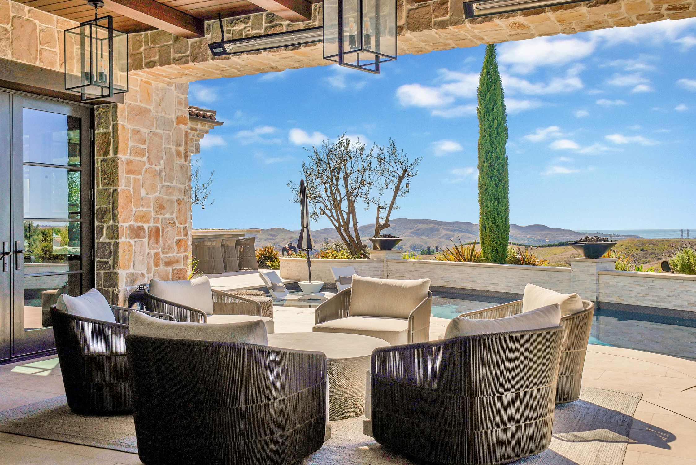 Outdoor lounge chairs beside pool and hillside view