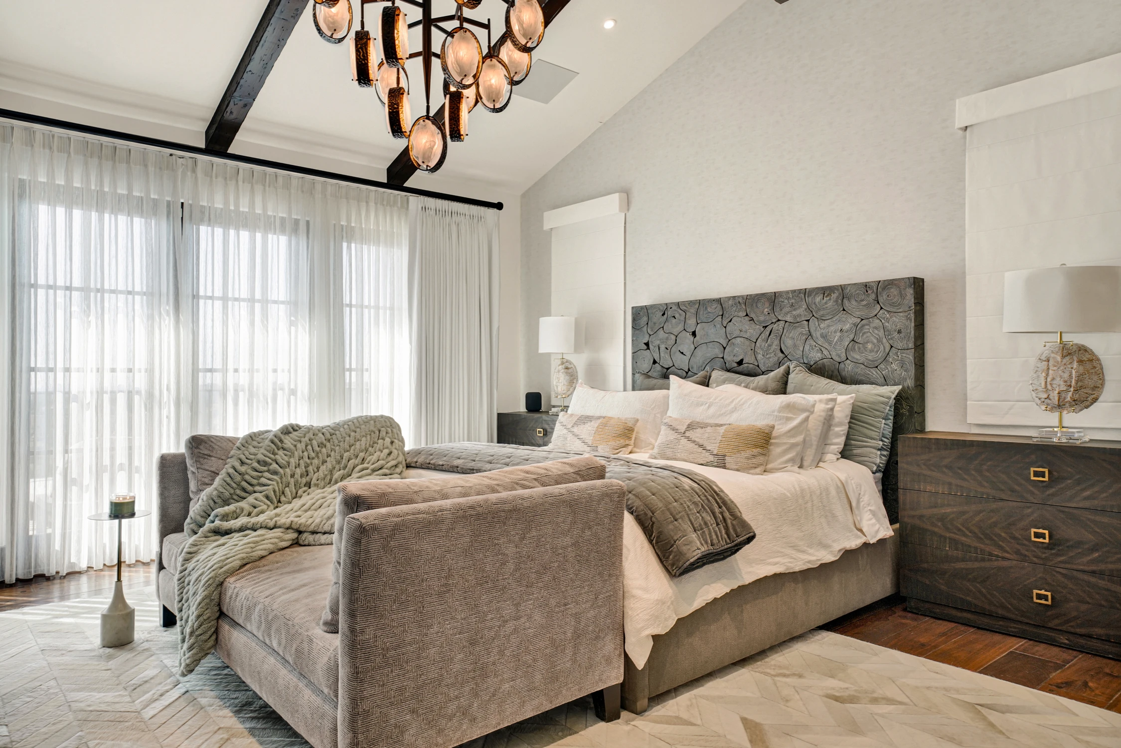 Primary bedroom with white upholstered bed and exposed beams