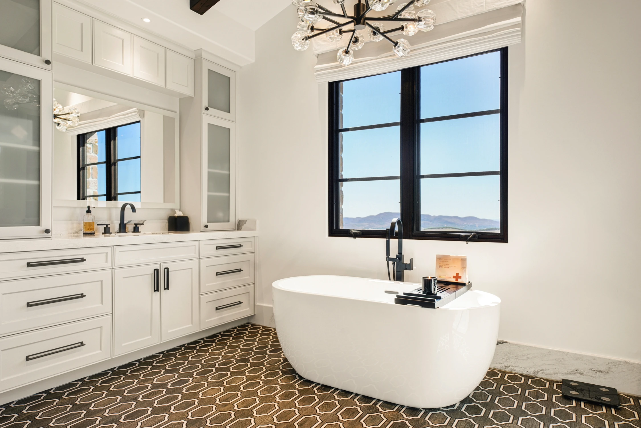 Primary bathroom with freestanding tub, white cabinetry, and patterned tile floor