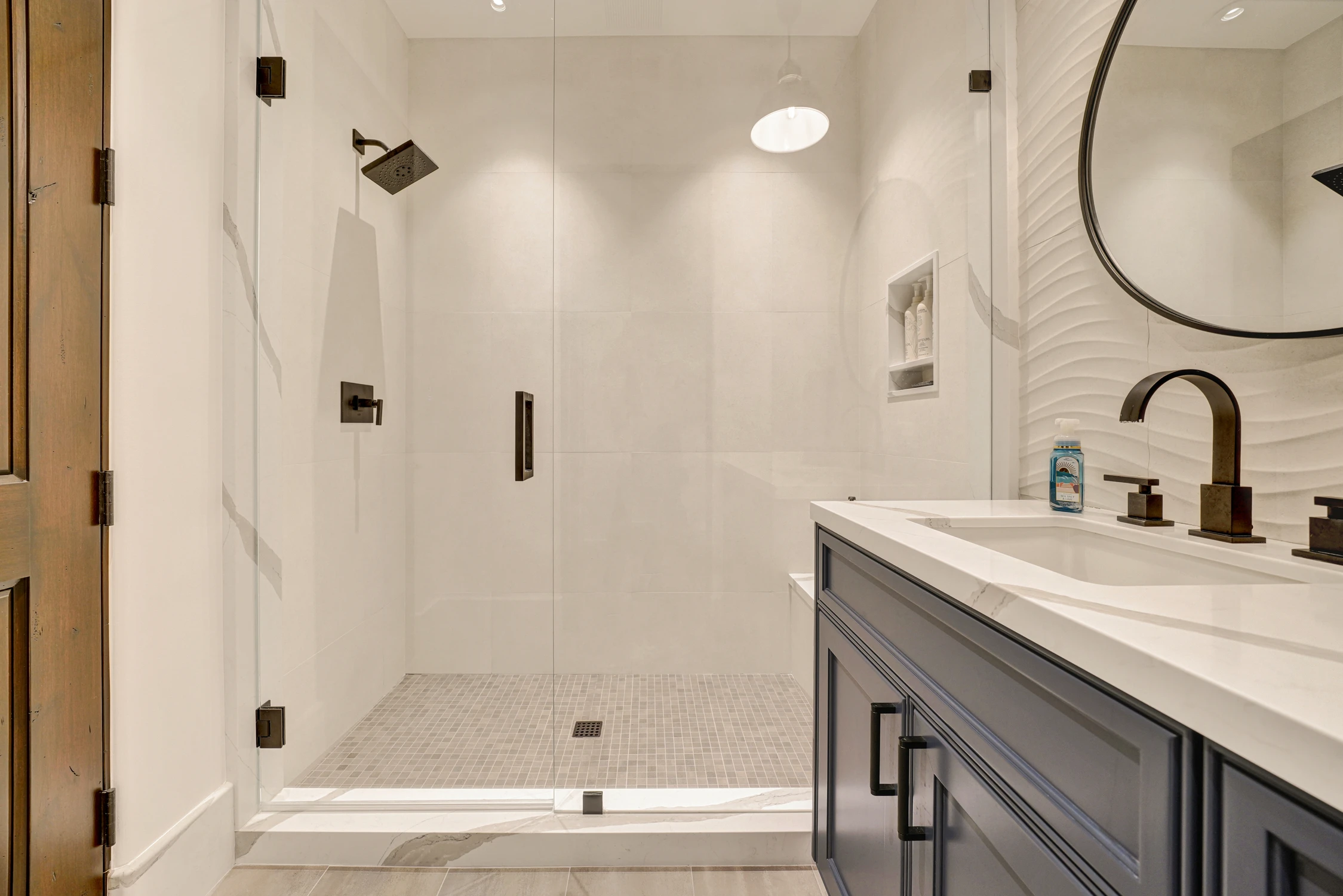 Bathroom with blue vanity, white tile shower, and black fixtures