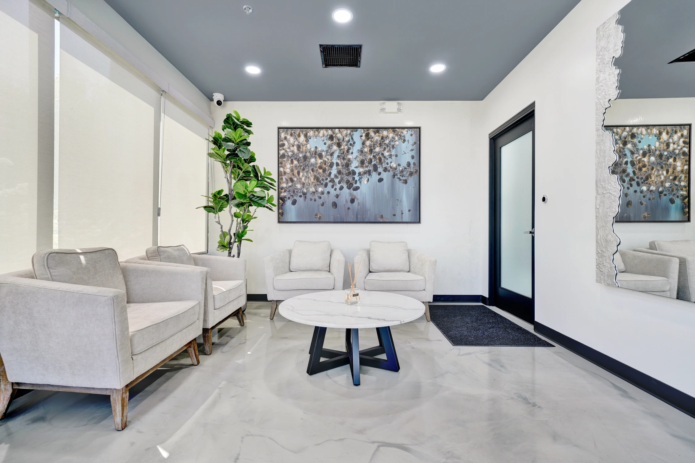 Reception lounge with white chairs, marble-look floor, and abstract artwork
