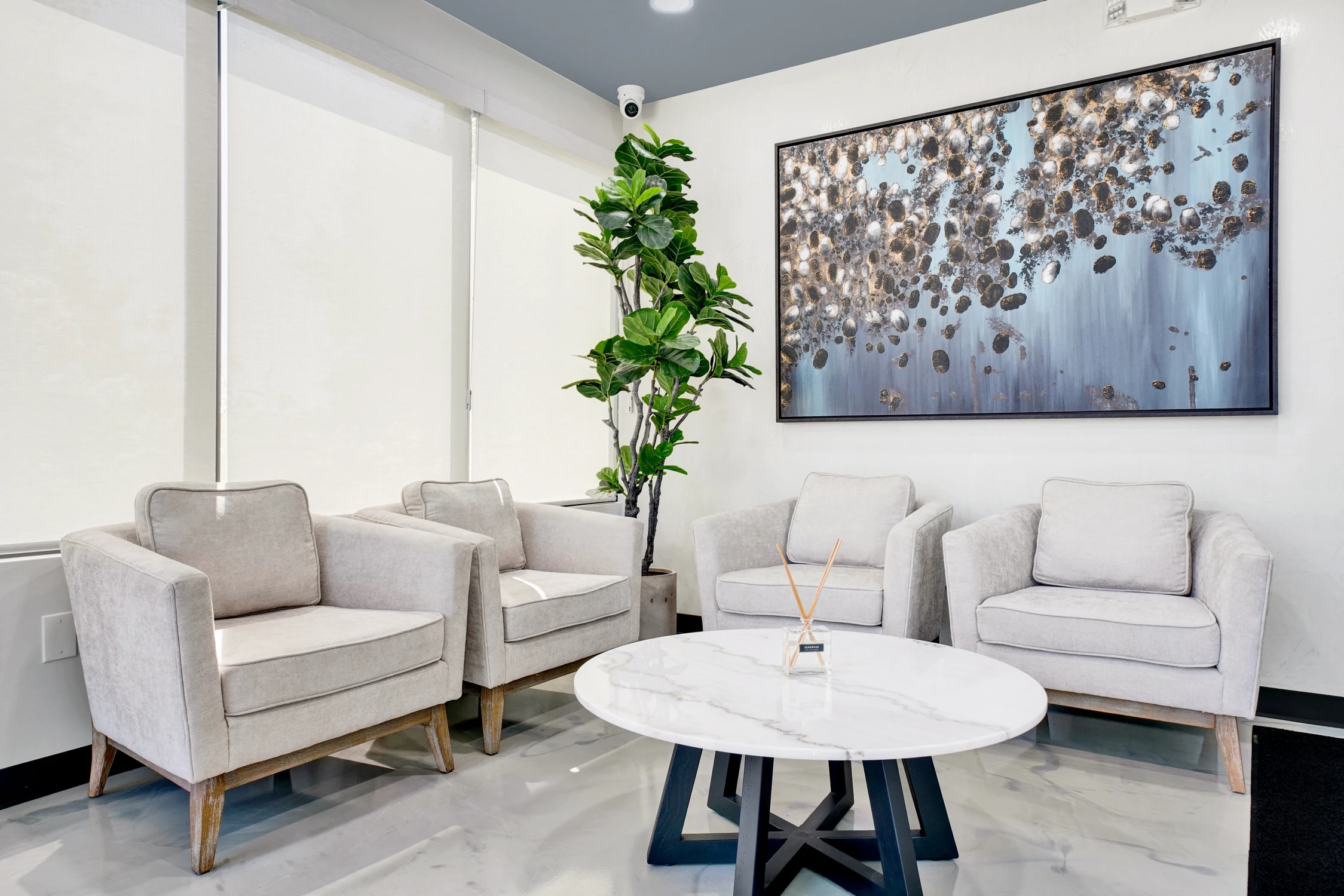 White reception seating beneath metallic abstract wall artwork
