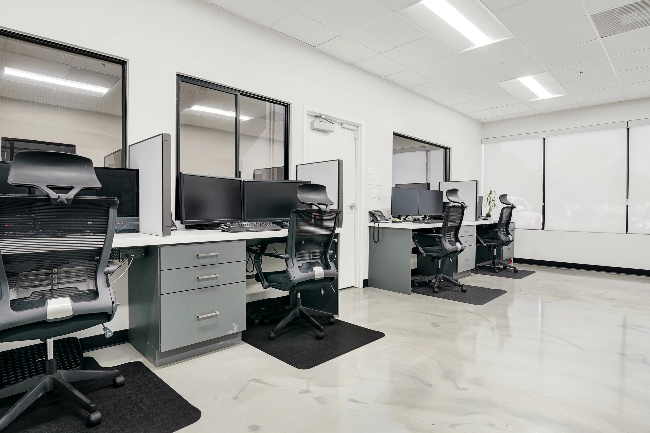 Open office with gray workstations and black-framed glass partitions