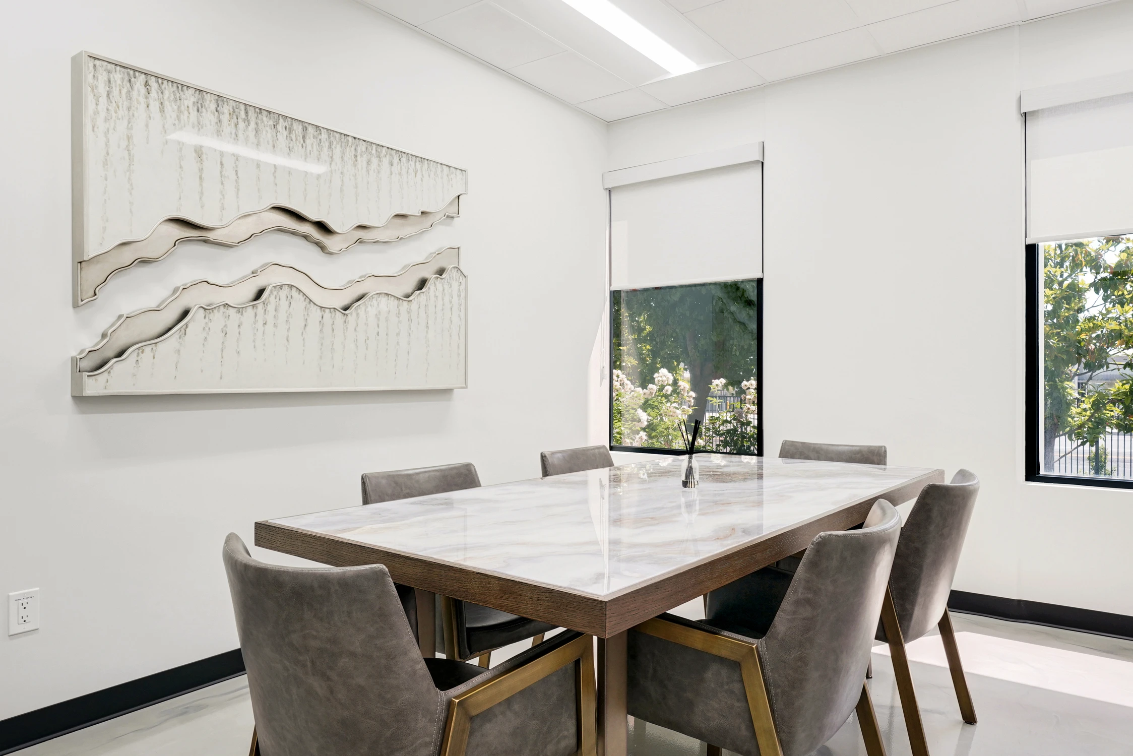 Small meeting table below white sculptural wall artwork