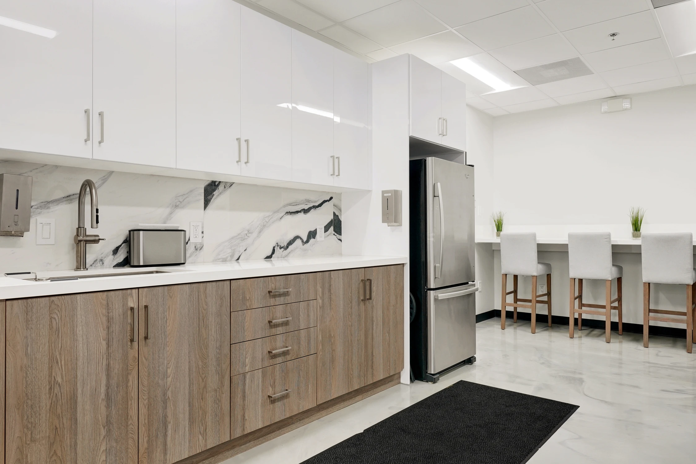 Staff kitchen with wood cabinetry, white counters, and café table