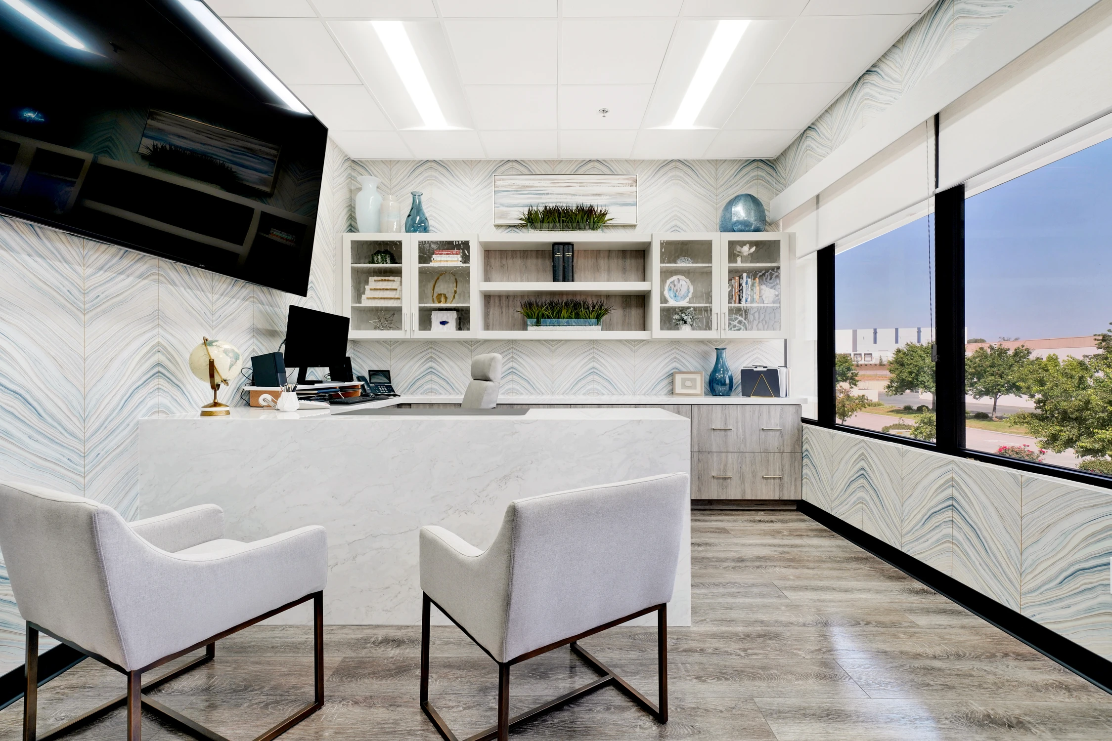 Office with marble desk, white chairs, and blue patterned wallcovering