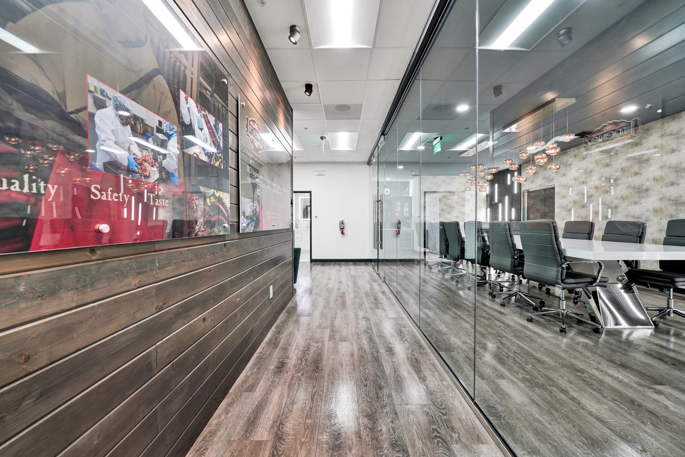Glass conference room beside wood-paneled hallway and company display