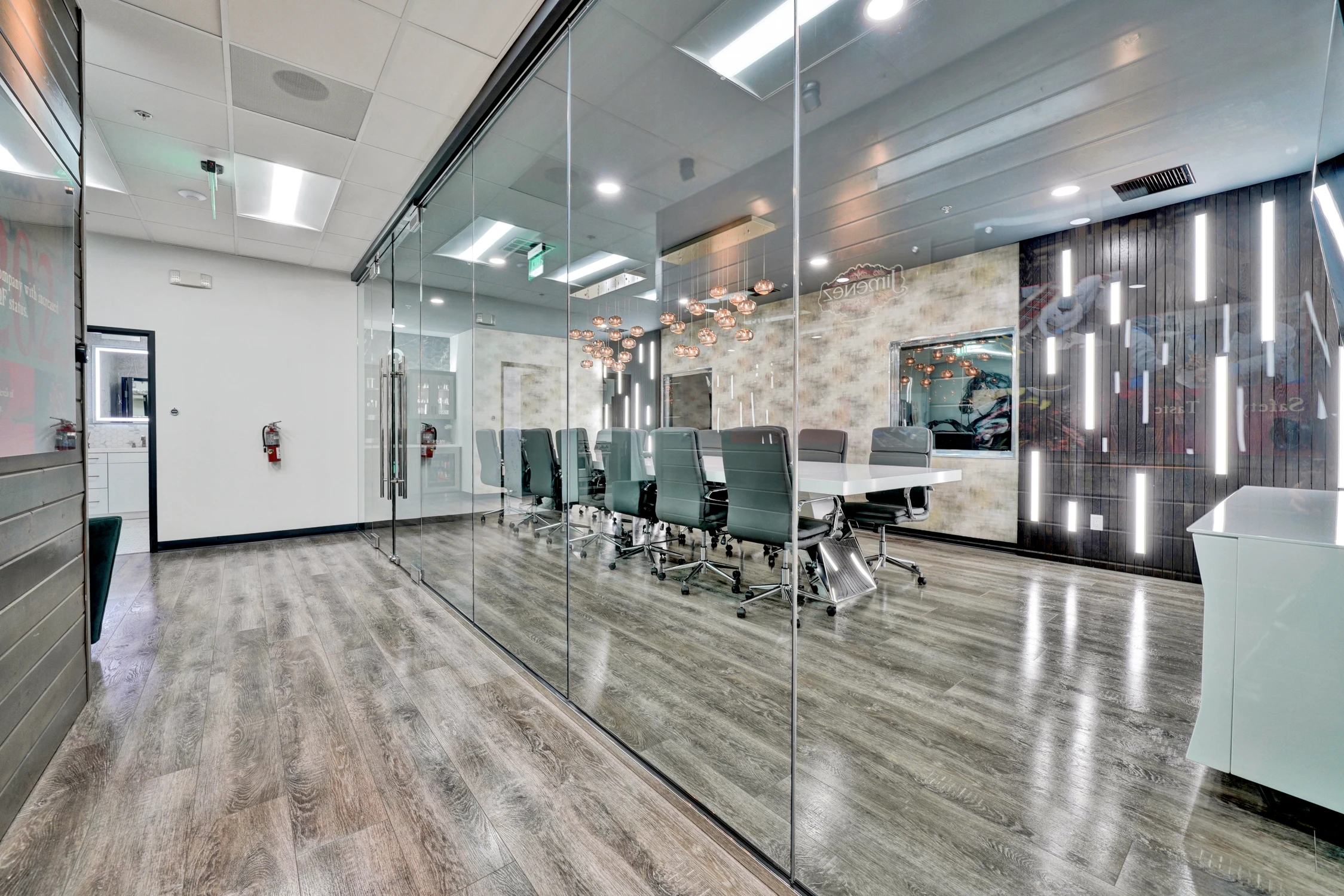 Glass conference room with illuminated wood wall and suspended pendants