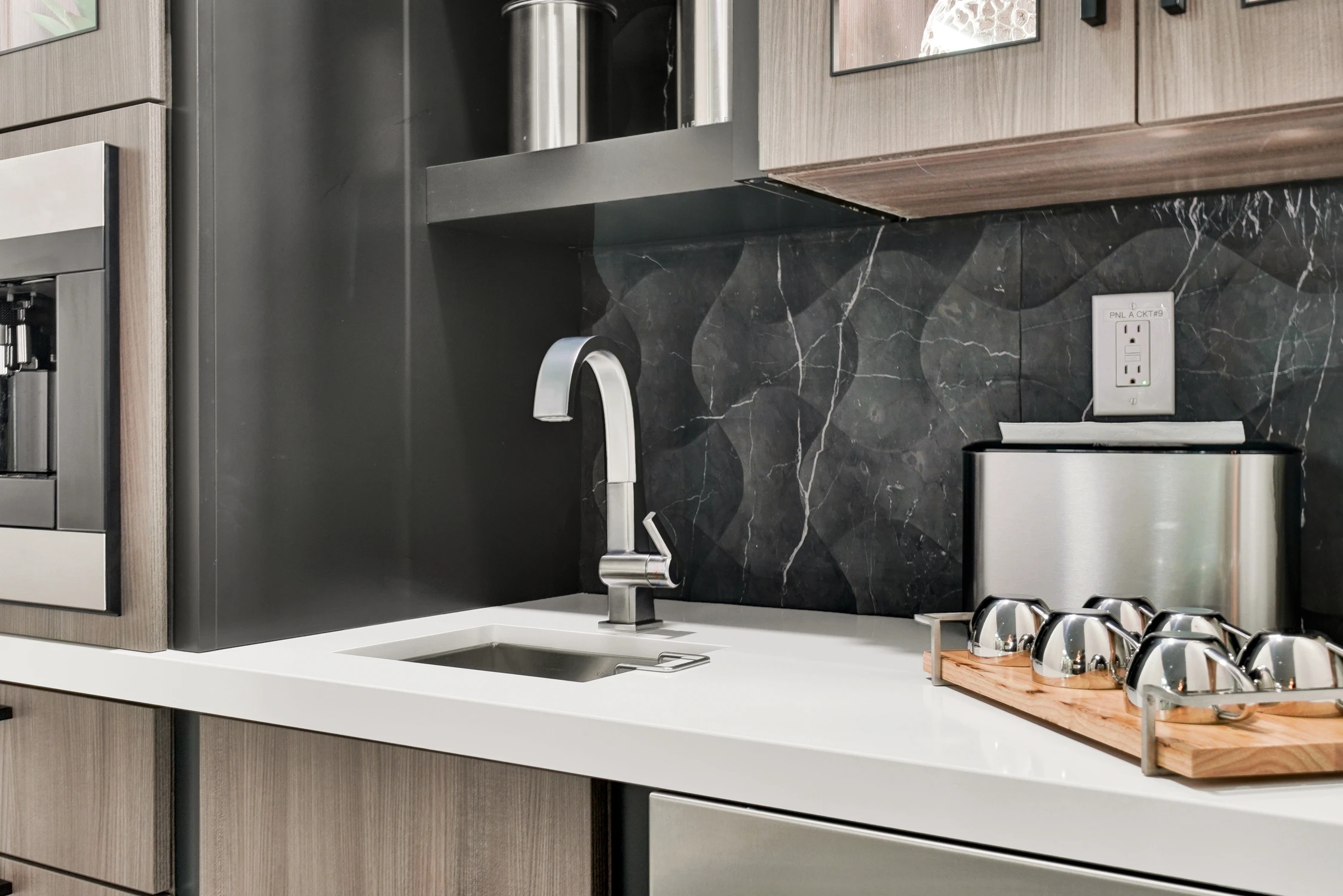 Close view of beverage sink against black stone-pattern backsplash