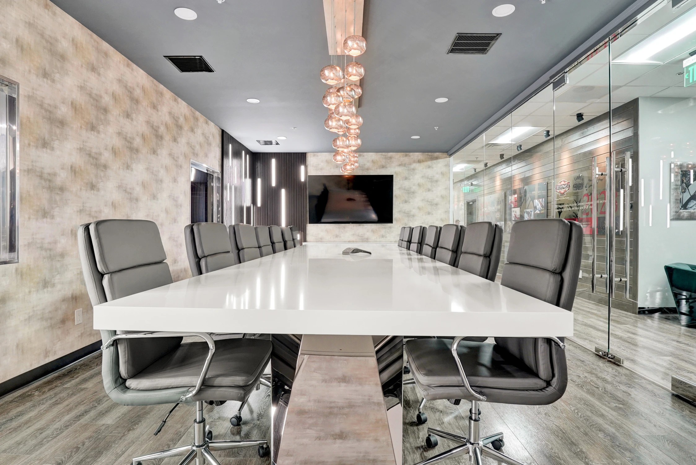 Long white conference table beneath clustered glass pendant lights