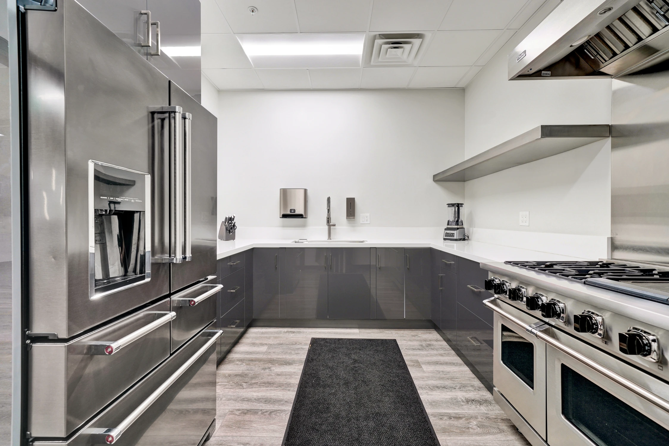 Commercial kitchen with stainless appliances and dark base cabinetry