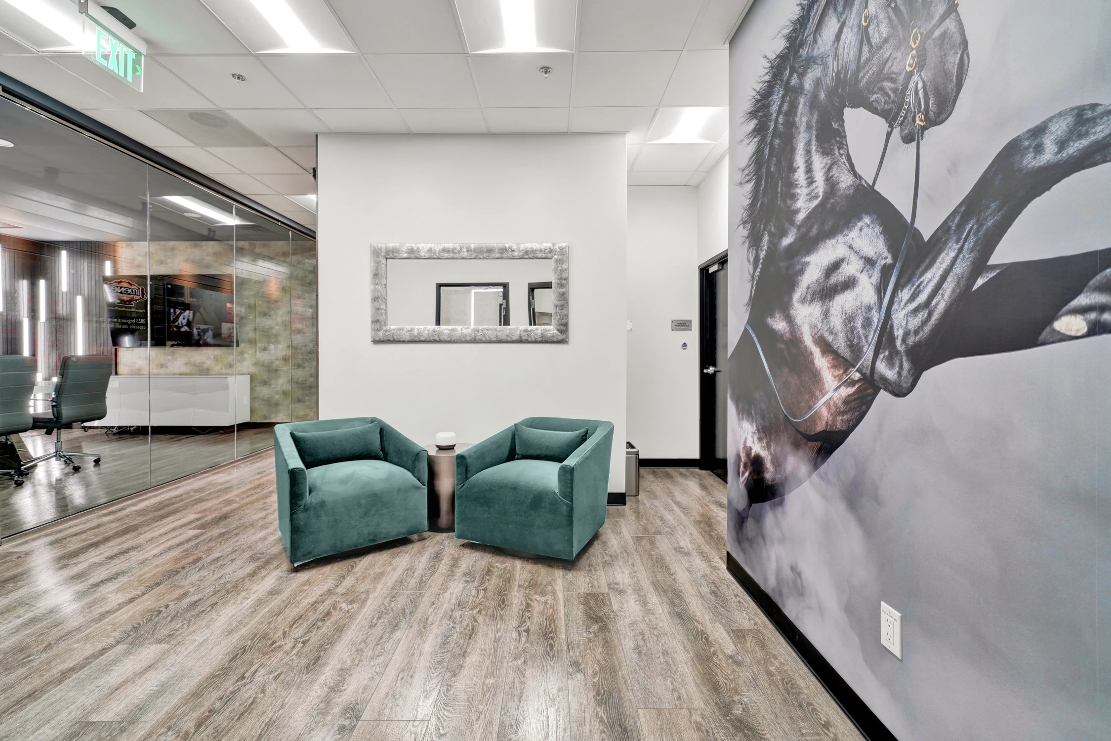Teal lounge chairs beside horse mural and framed mirror