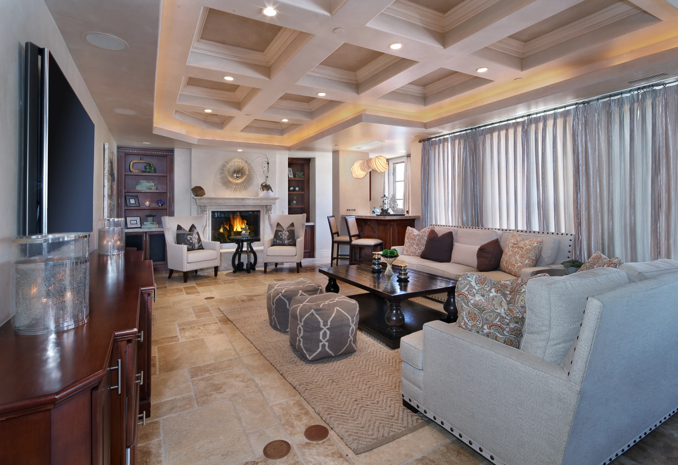 Living room with coffered ceiling, fireplace, and layered seating