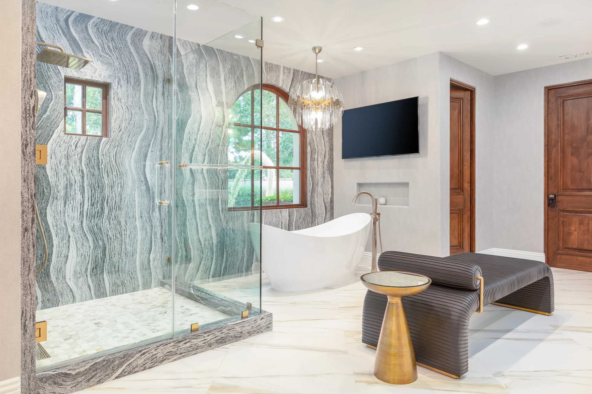 Primary bathroom with glass shower, freestanding tub, and window